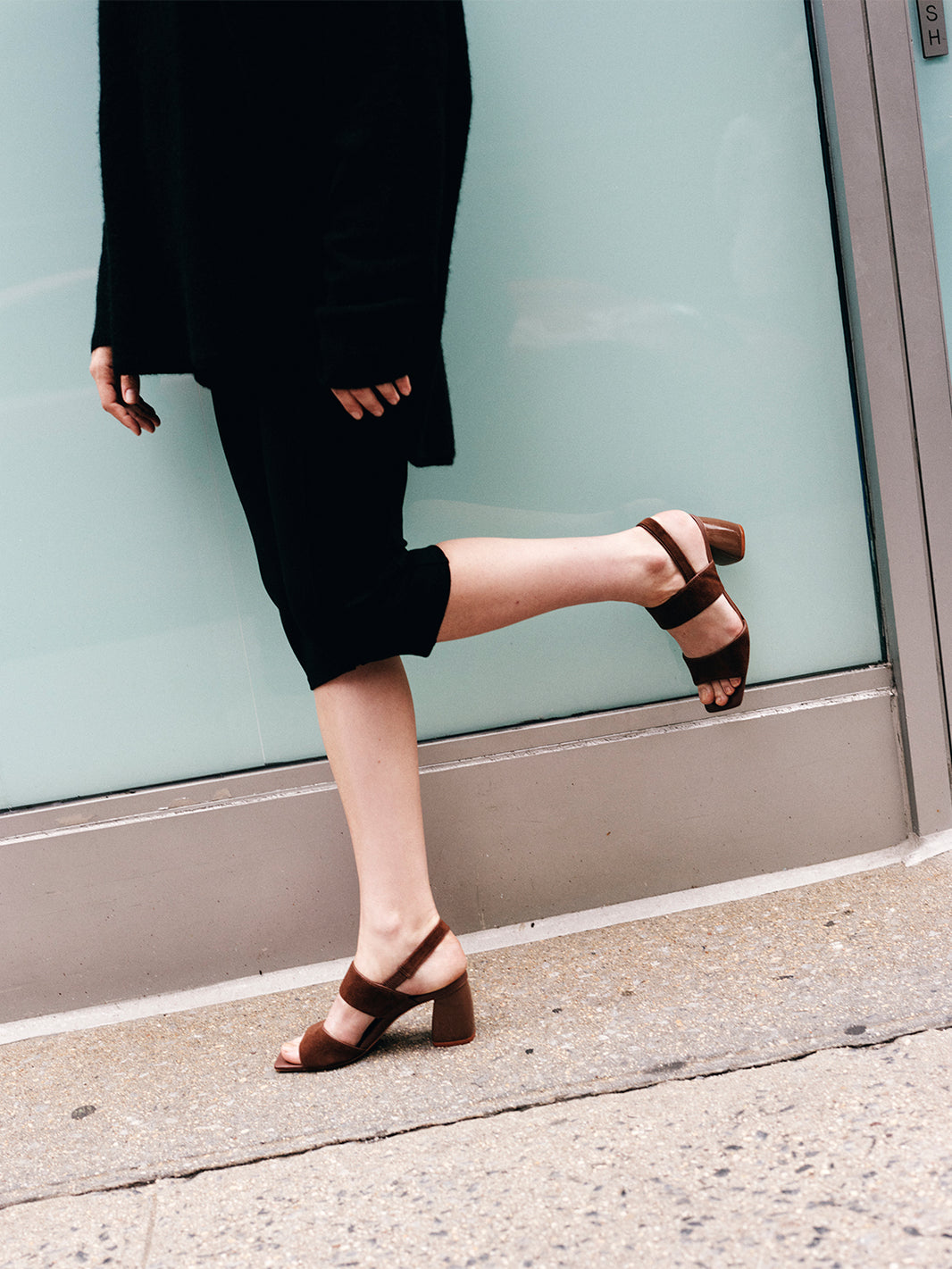 Side view of a mocha brown suede block heel sandal, shown on a model.