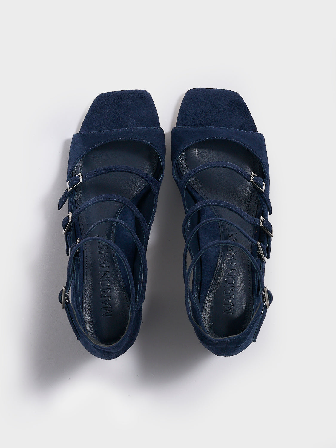 Top view of a pair of navy blue suede block heel mary jane sandals with adjustable straps and a square toe.