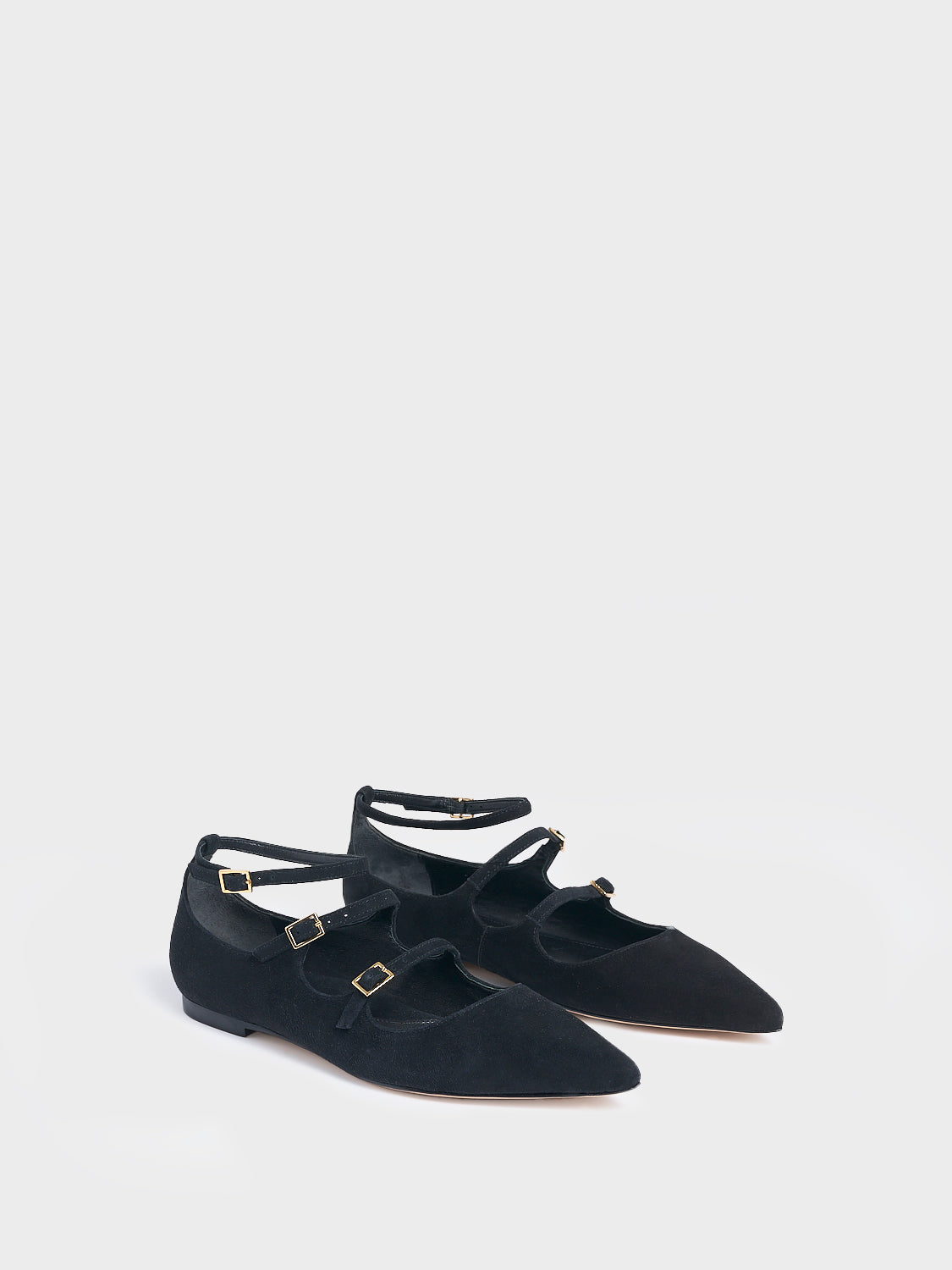Angle view of a pair of black suede mary jane flats with adjustable straps and a pointed toe.