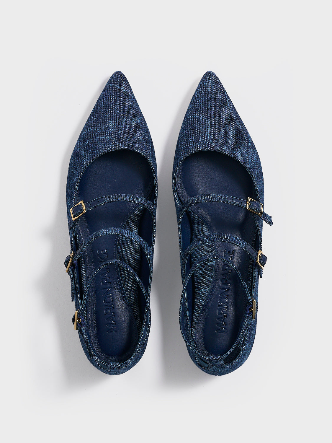 Top view of a pair of navy denim mary jane flats with adjustable straps and a pointed toe.