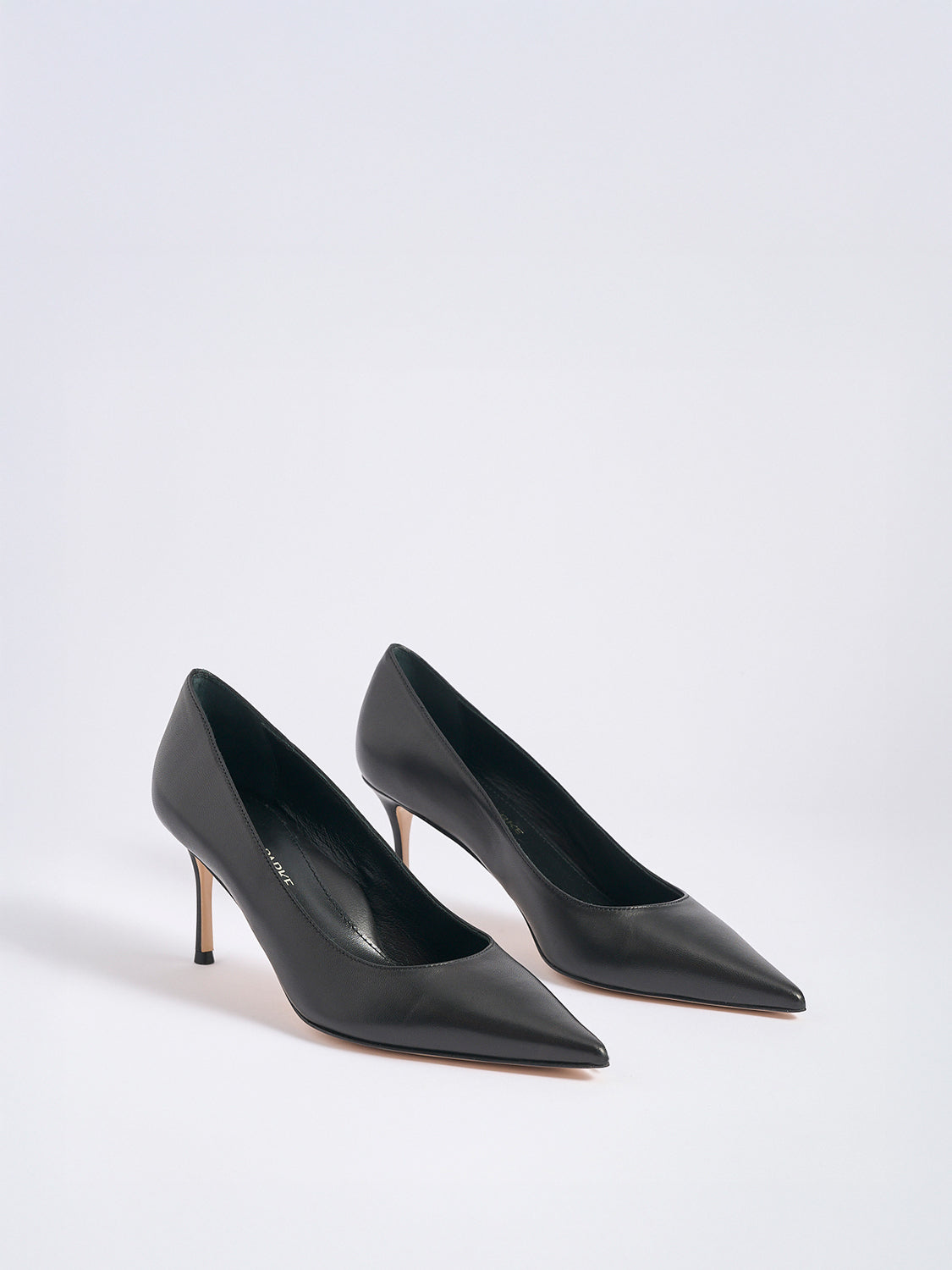 Angle view of a pair of black leather stiletto heel pumps with a pointed toe.