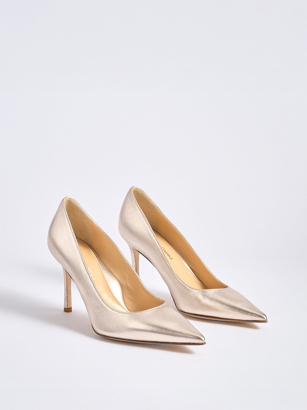Angle view of a pair of gold leather high stiletto heel pumps with a pointed toe.