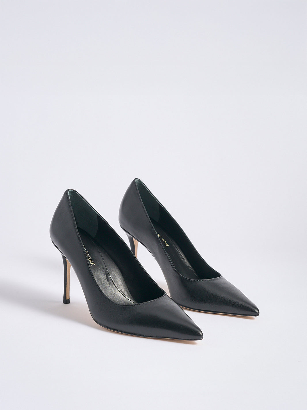 Angled view of a pair of black leather high stiletto heel pumps with a pointed toe.