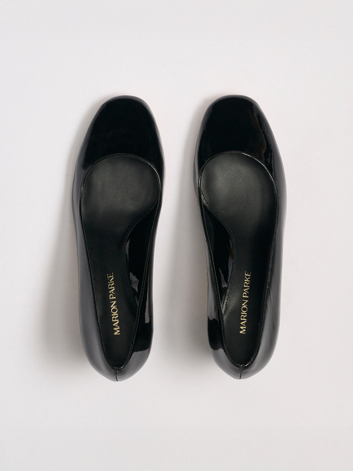 Top view of a pair of black patent leather block heel pumps with a rounded toe.