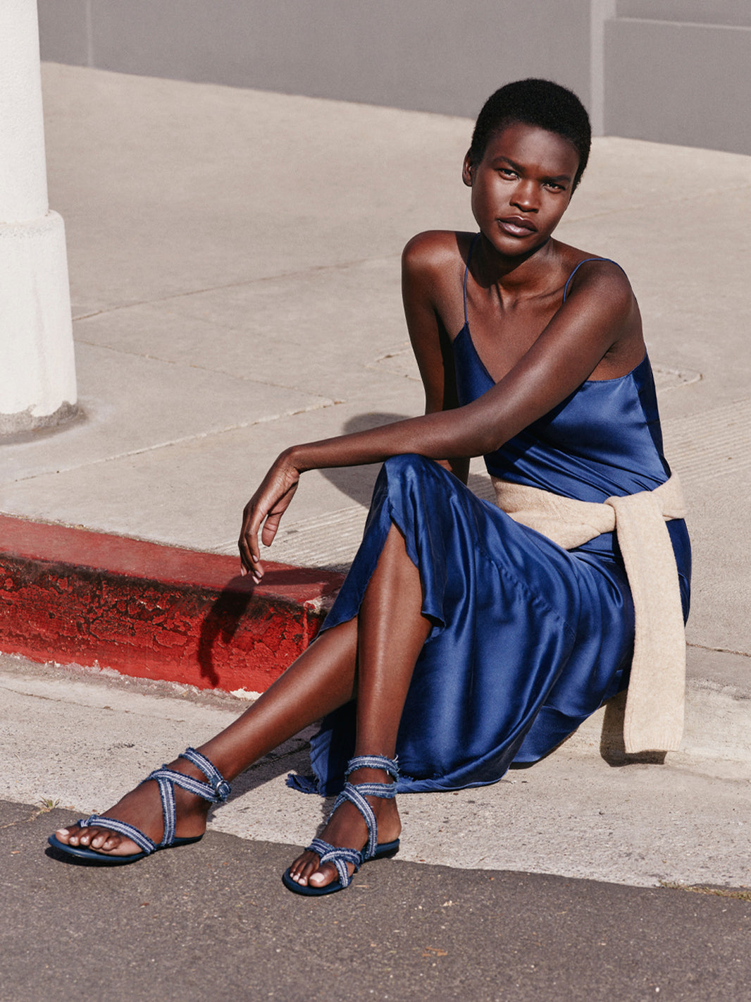 Angled view of a navy blue denim thong flat sandal with a rounded toe, shown on model