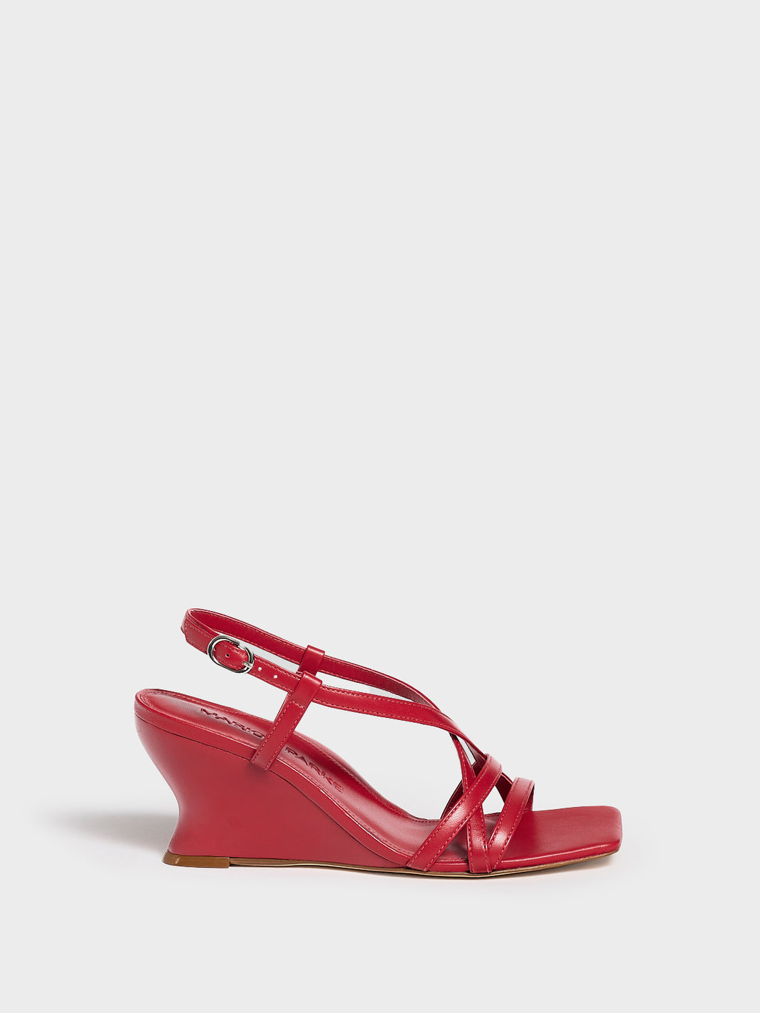 Profile view of a lipstick red leather strappy sandal with a sculptural wedge.