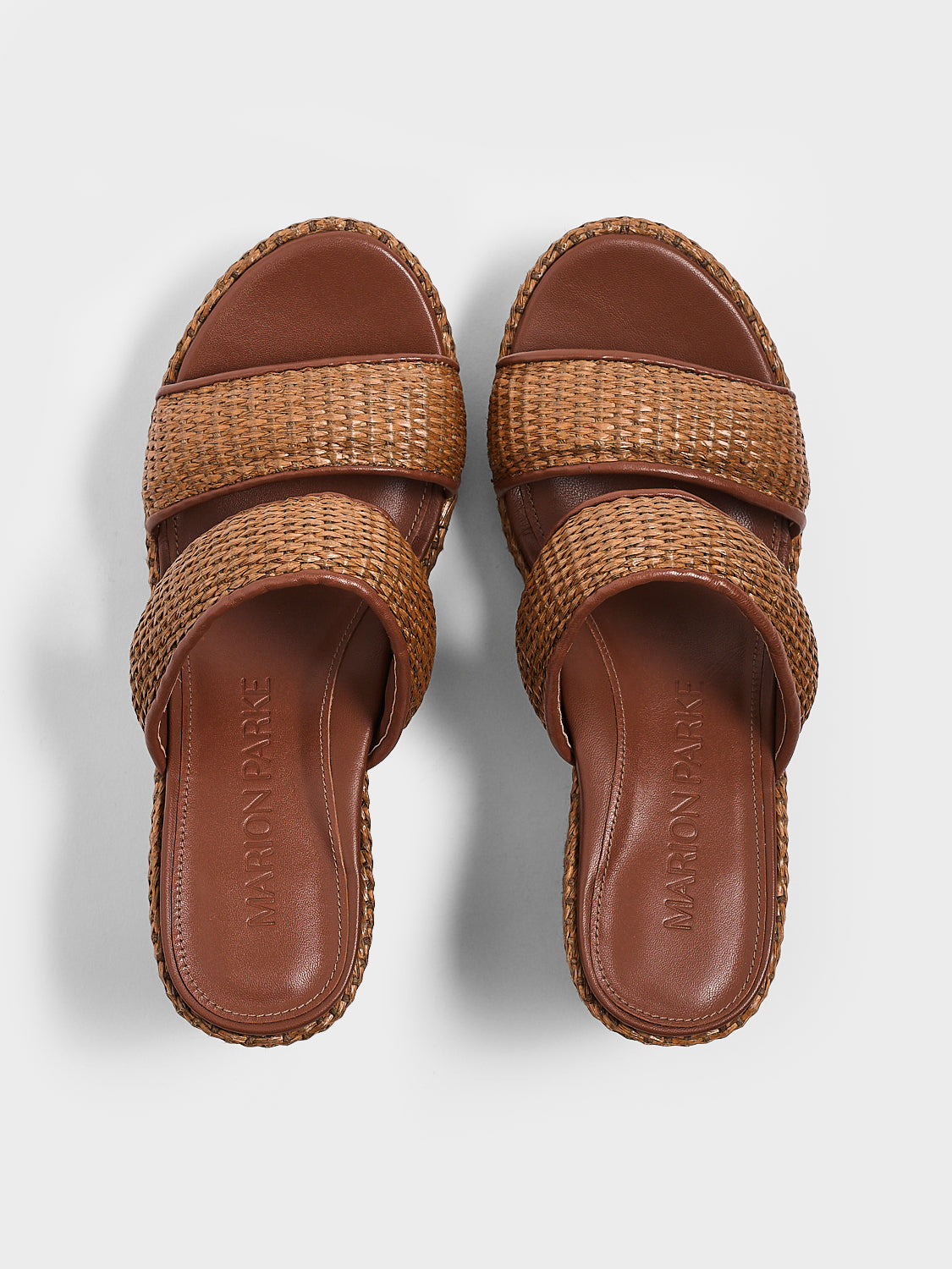 Top view of a pair of dark brown raffia platform sandals with a leather trim and puffed straps.