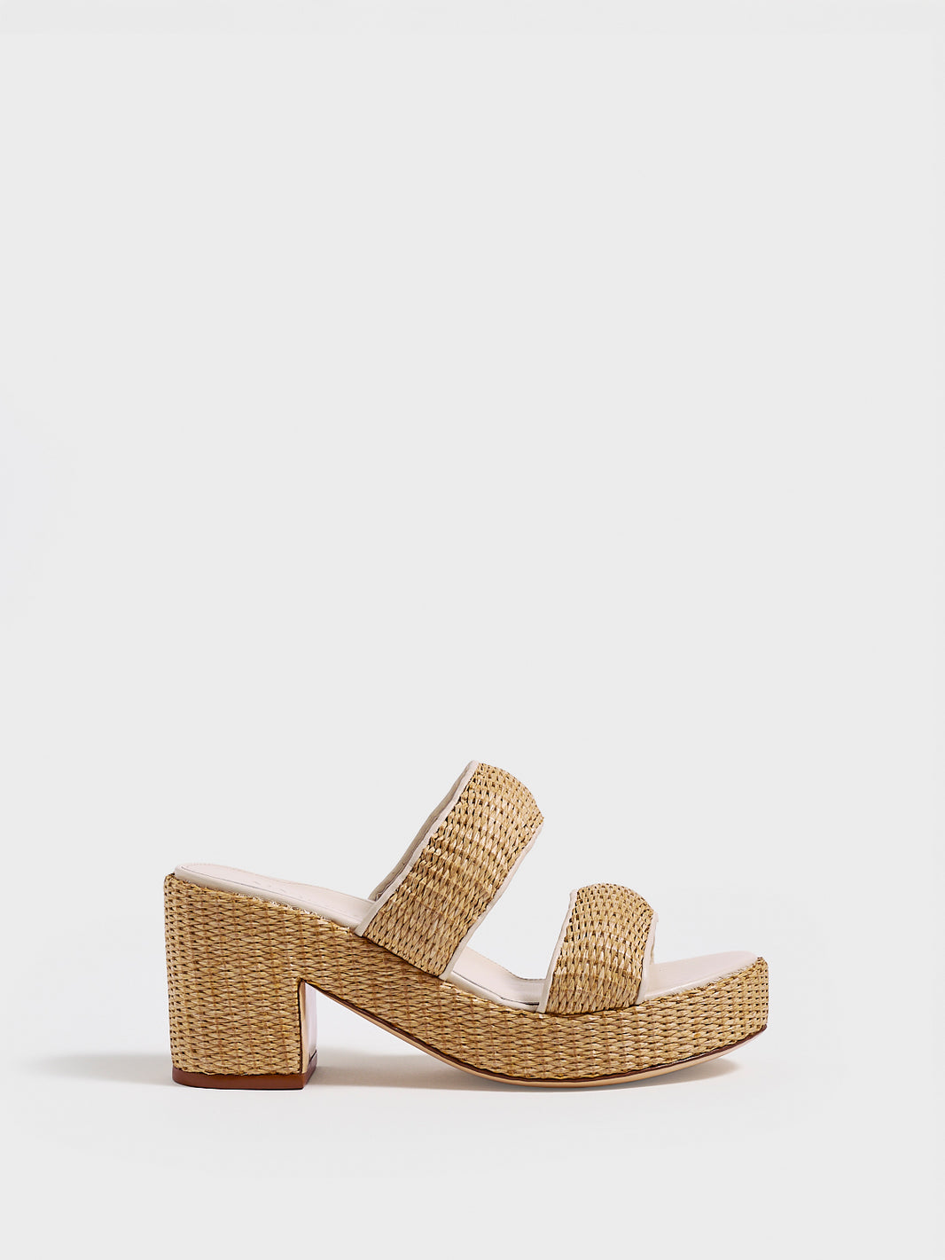 Profile view of a raffia platform sandal with a light cream leather trim and puffed straps.