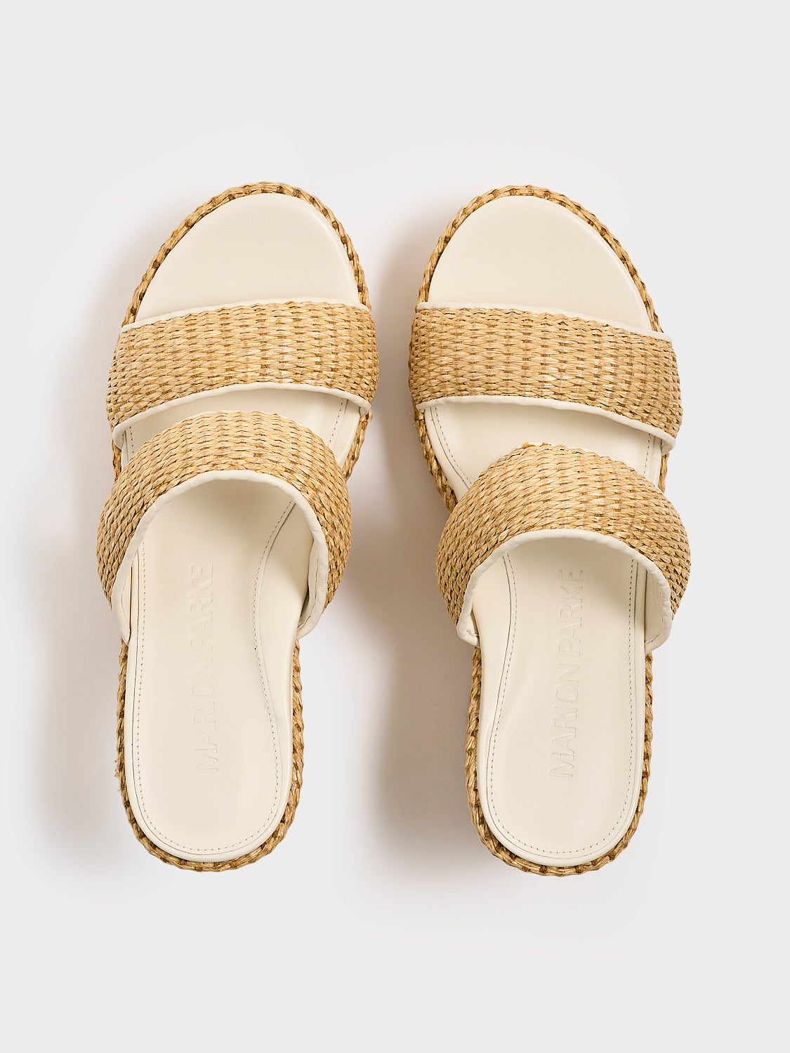 Top view of a pair of raffia platform sandals with a light cream leather trim and puffed straps.