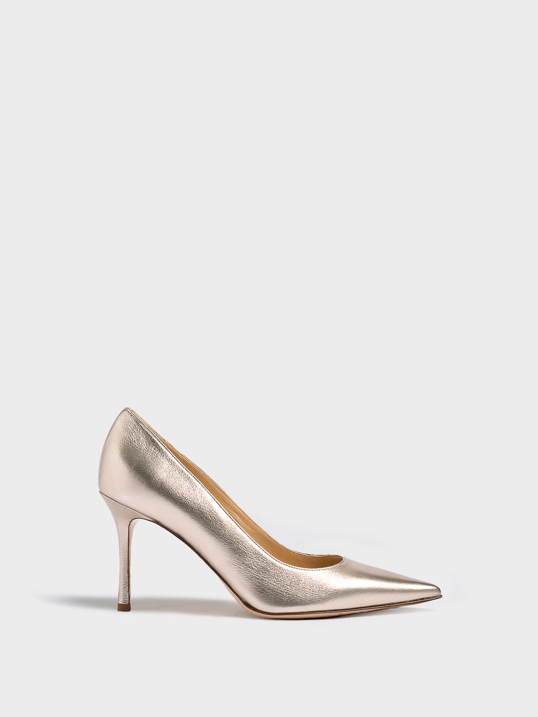 Profile view of a soft gold metallic high stiletto heel pump with a pointed toe.