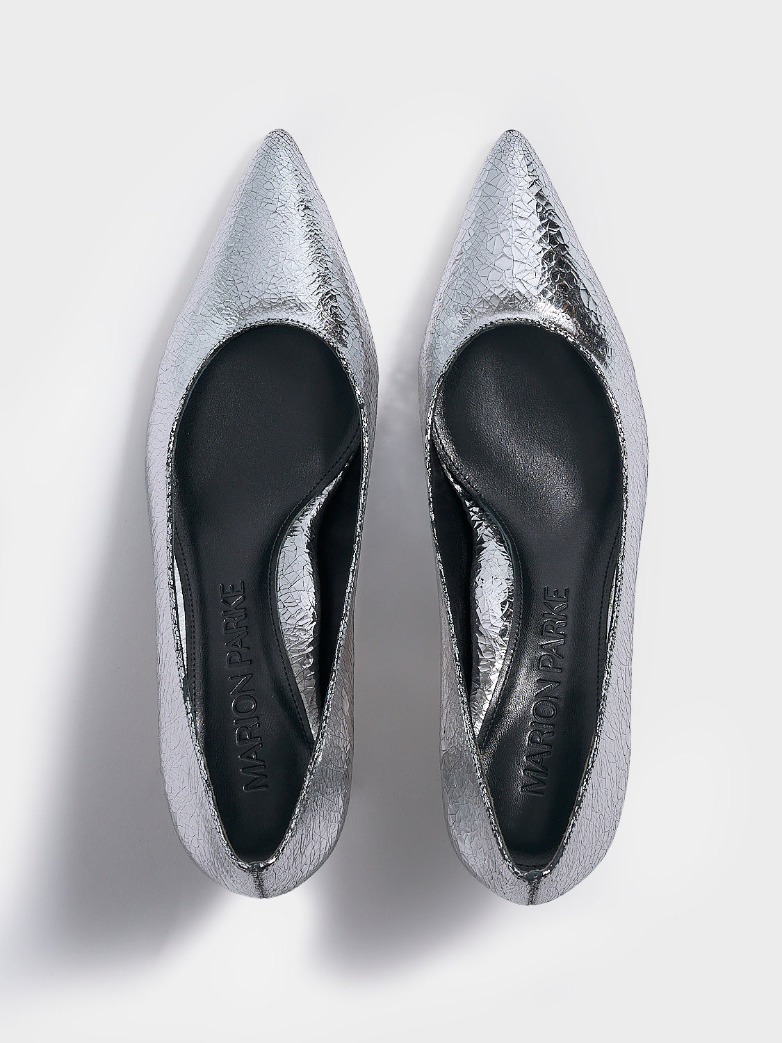 Top view of a pair of silver metallic leather flared kitten heel pumps with a pointed toe.