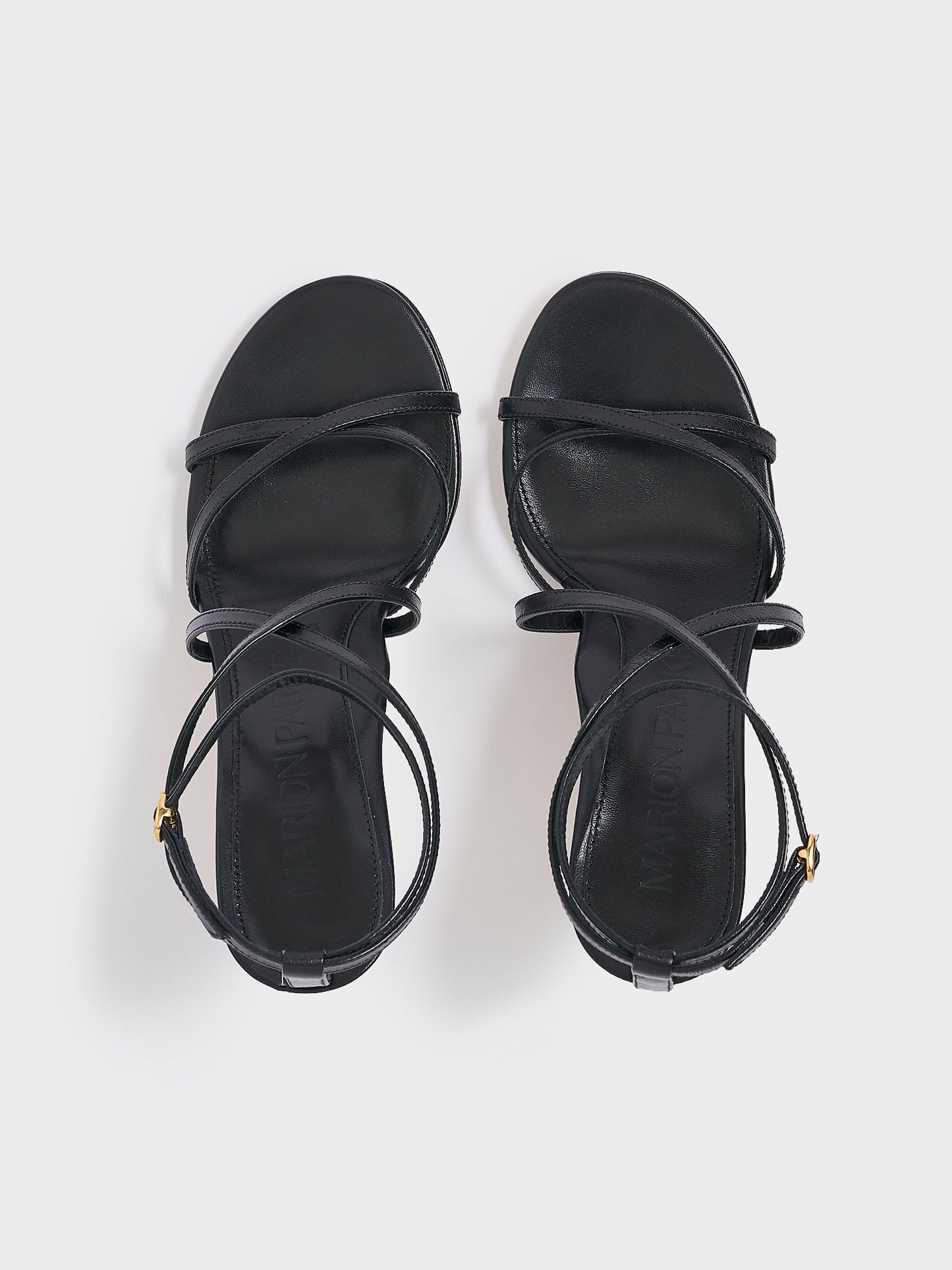 Top view of a pair of black leather high heel strappay sandals with an ankle strap detail.