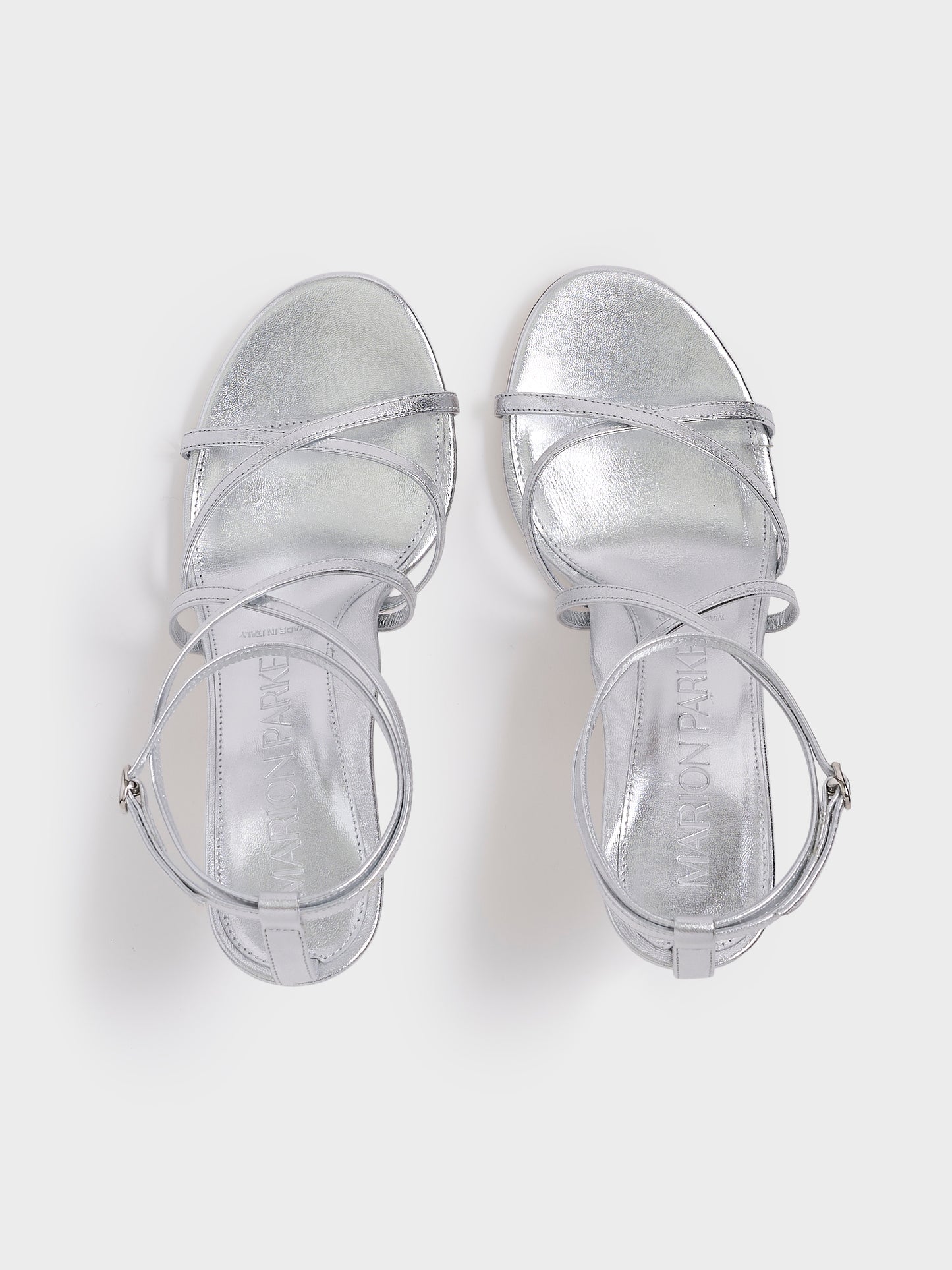 Top view of a pair of silver metallic leather high heel strappy sandals with an ankle strap detail.