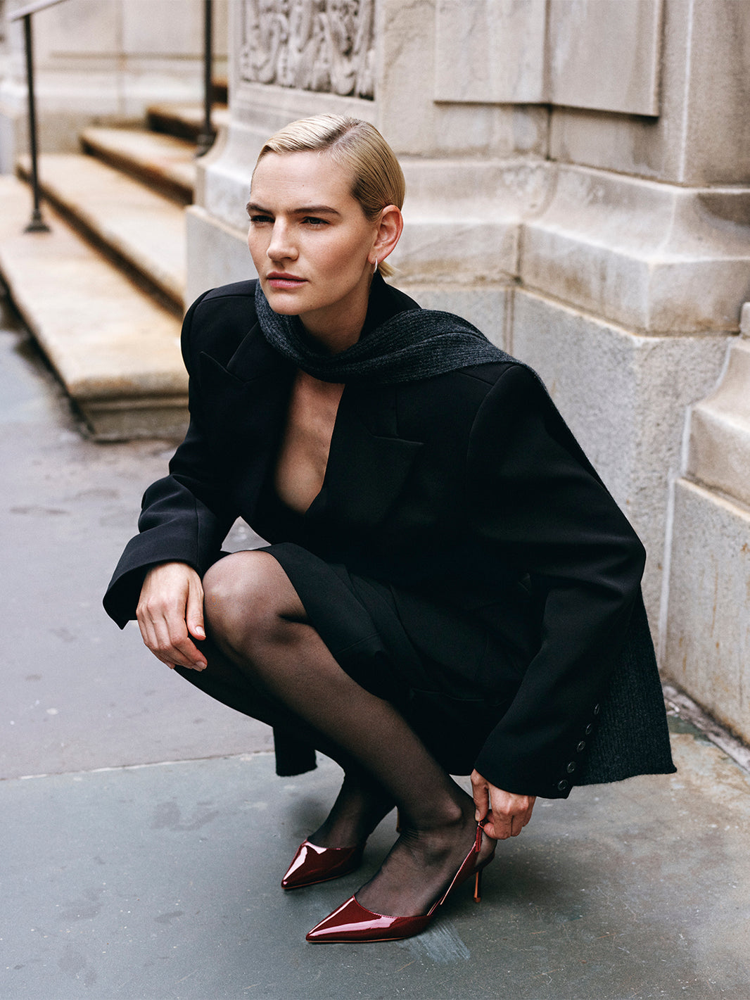 Side view of merlot red patent leather slingback heels with a pointed toe, shown on model.