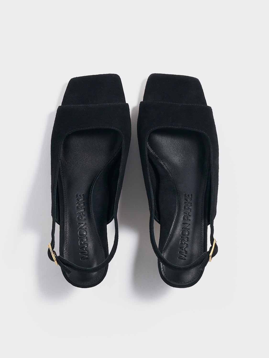 Top view of a pair of black suede slingback sandals with a flared kitten heel and square toe detail.