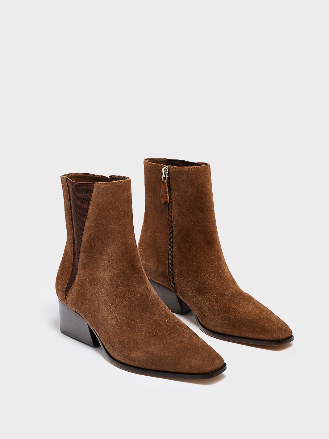 Angle view of a pair of mocha brown suede chelsea ankle bootie with a zipper closure, square toe, and block heel. 