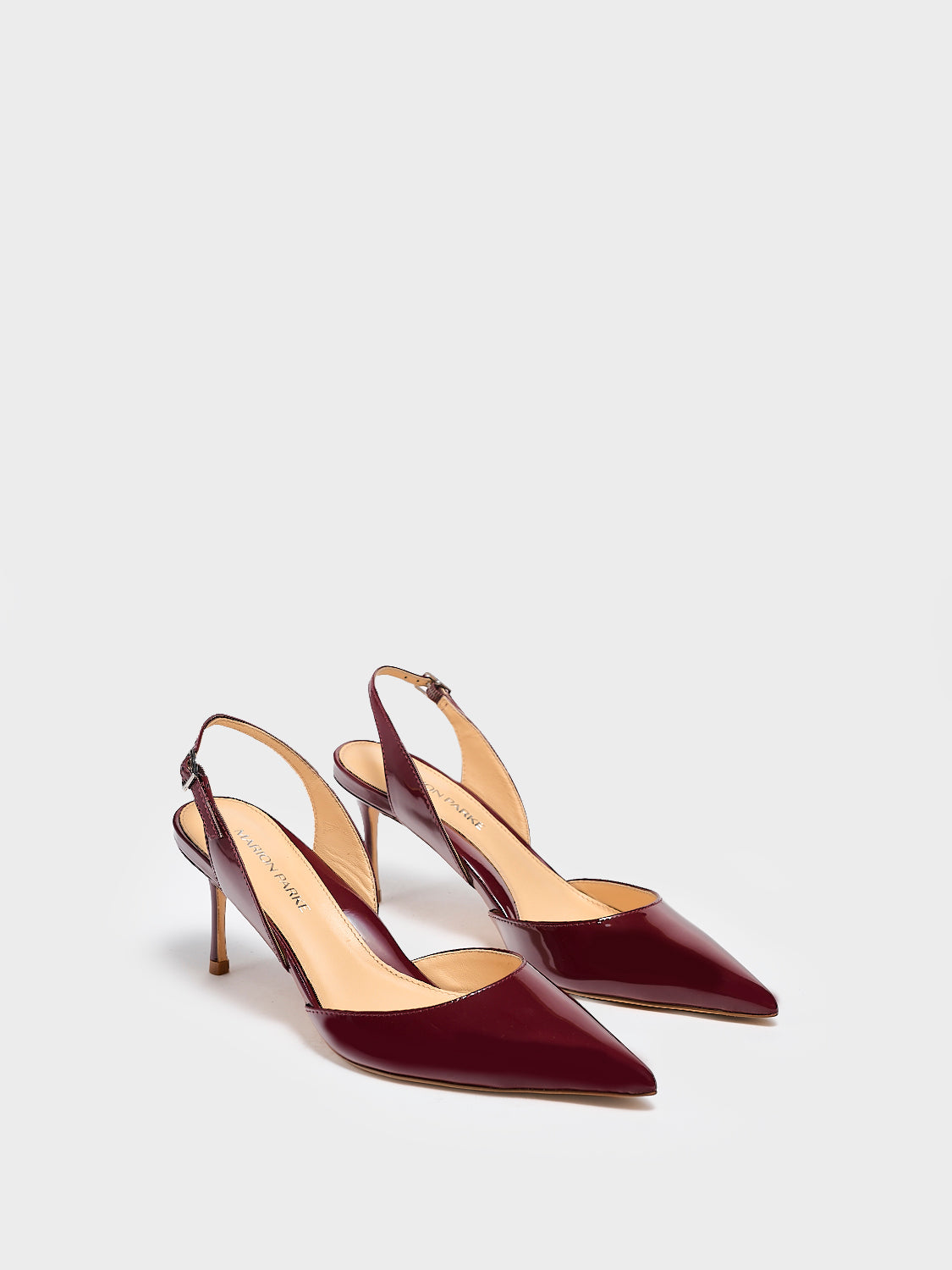 Angle view of a pair of merlot red patent leather slingback heel with a pointed toe.