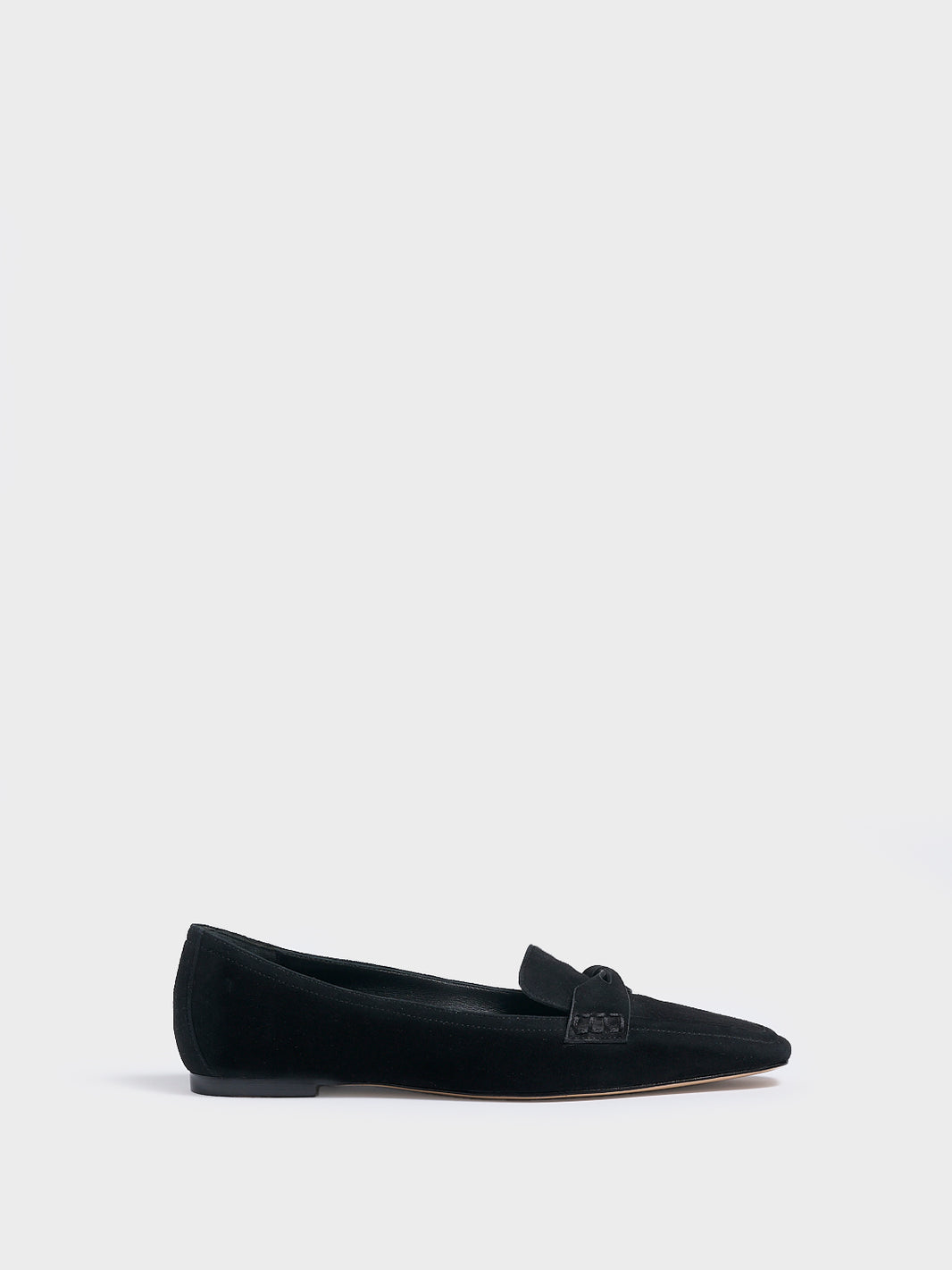 Profile view of a black suede penny loafer with a twist detail.