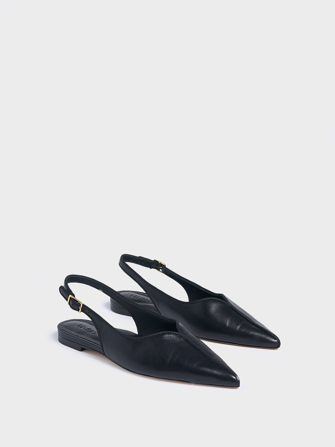 Angle view of a pair of black leather slingback flats with a grosgrain trim detail.