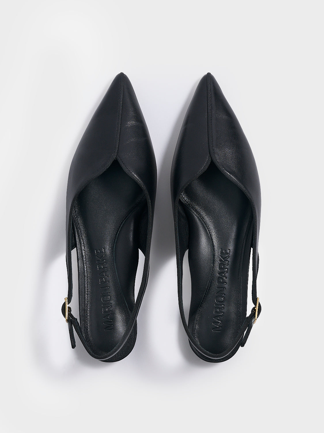 Top view of a pair of black leather slingback flats with a grosgrain trim detail.