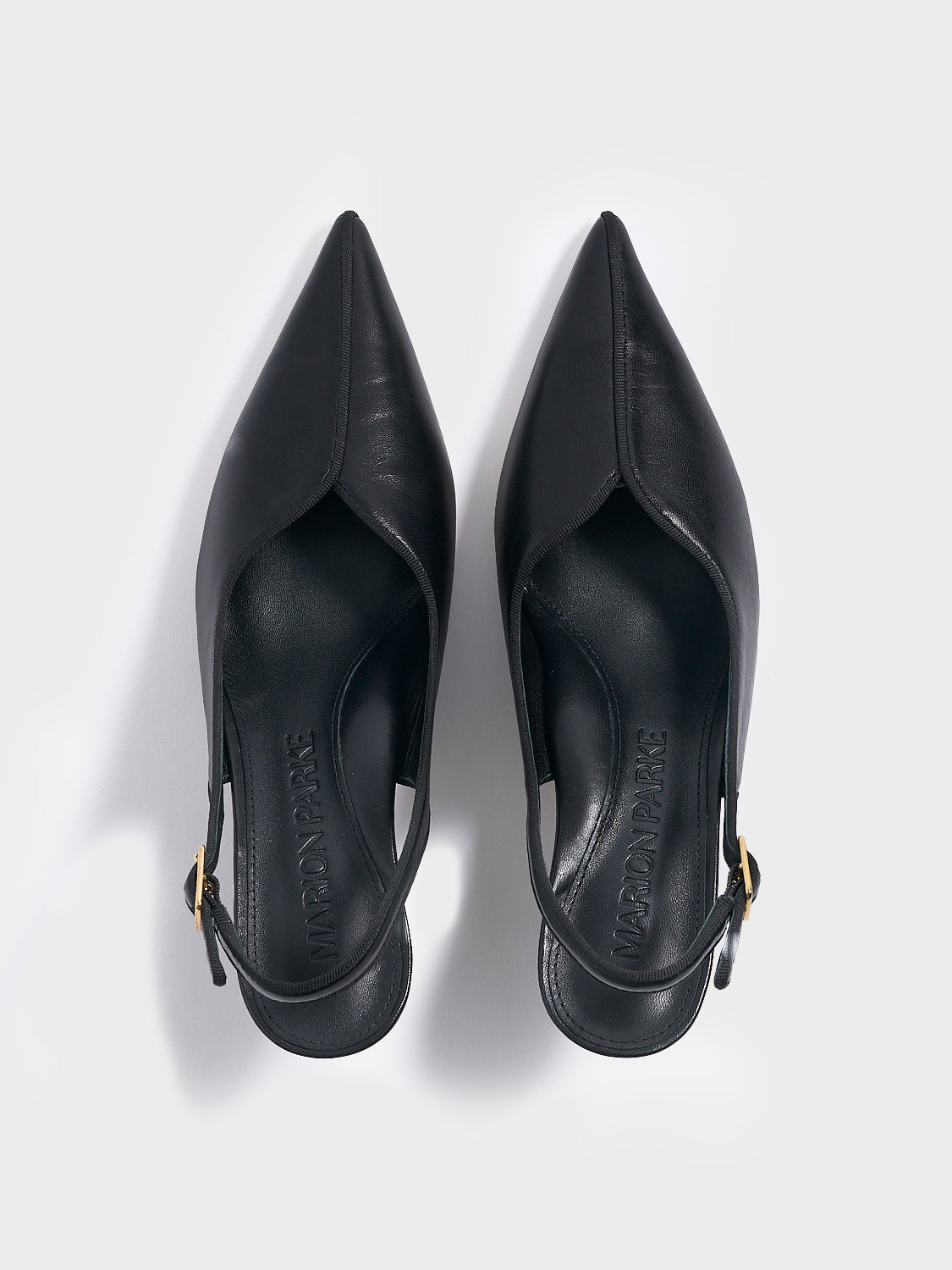 Top view of a pair of black  leather slingback kitten heels with a grosgrain trim and angled heel detail.
