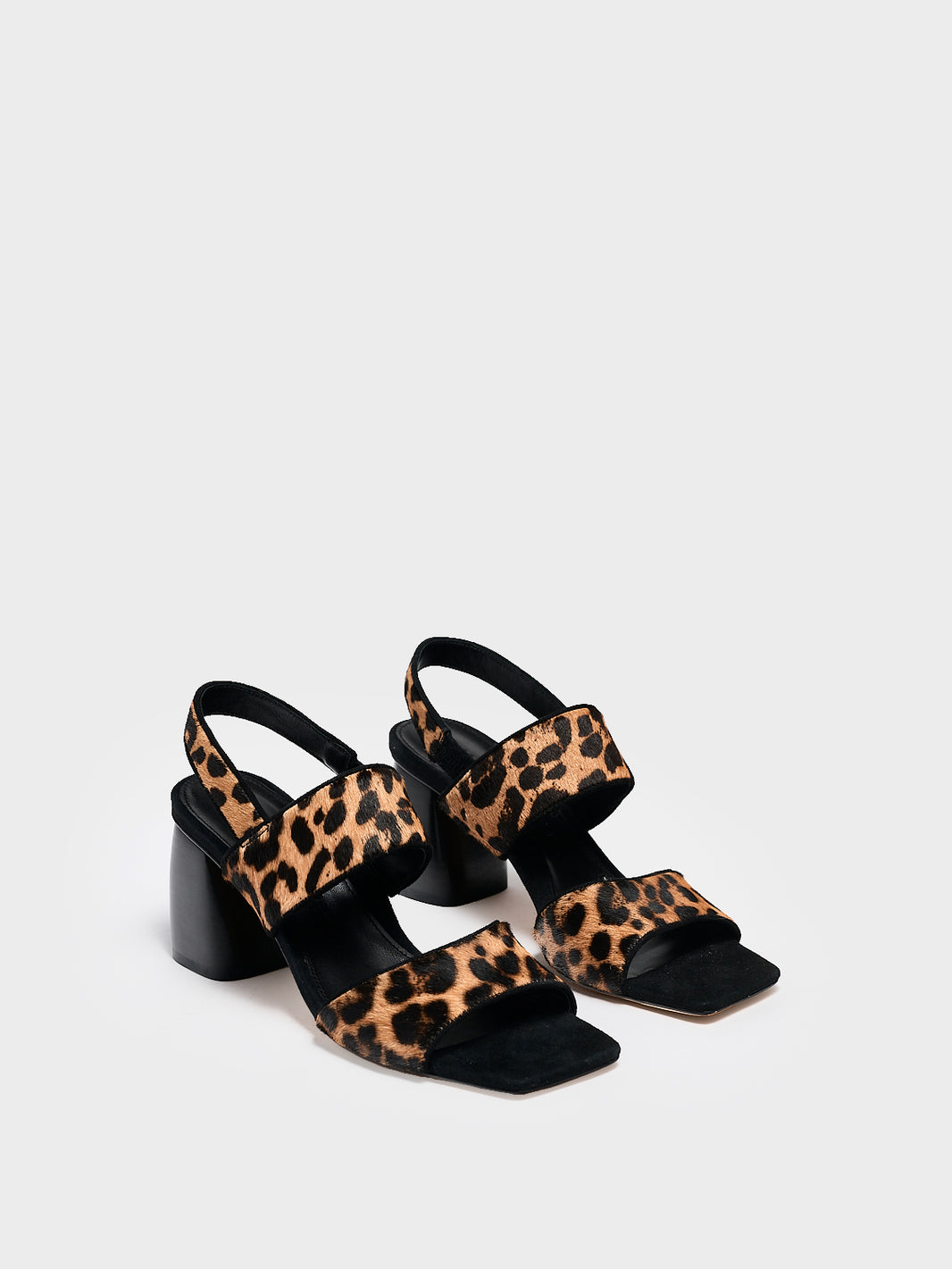 Angle view of a pair of leopard print hair calf block heel sandals with two over the foot straps and a square toe. 