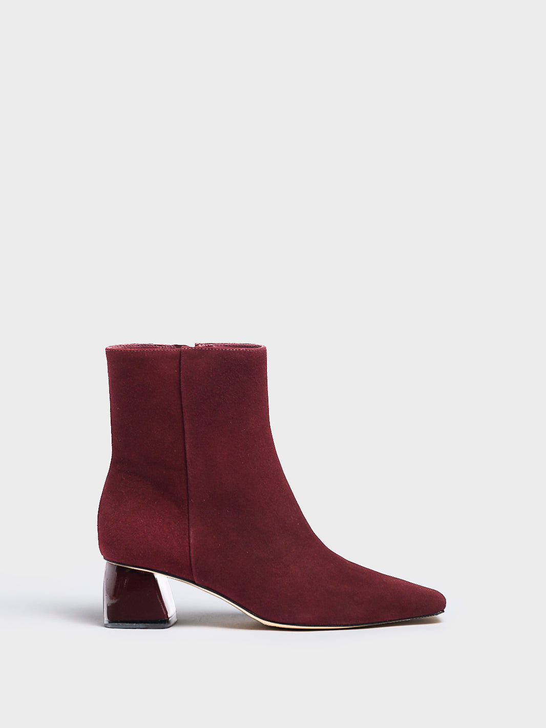 Profile view of a merlot suede ankle bootie with a rounded heel shape, zipper closure, and square toe. 