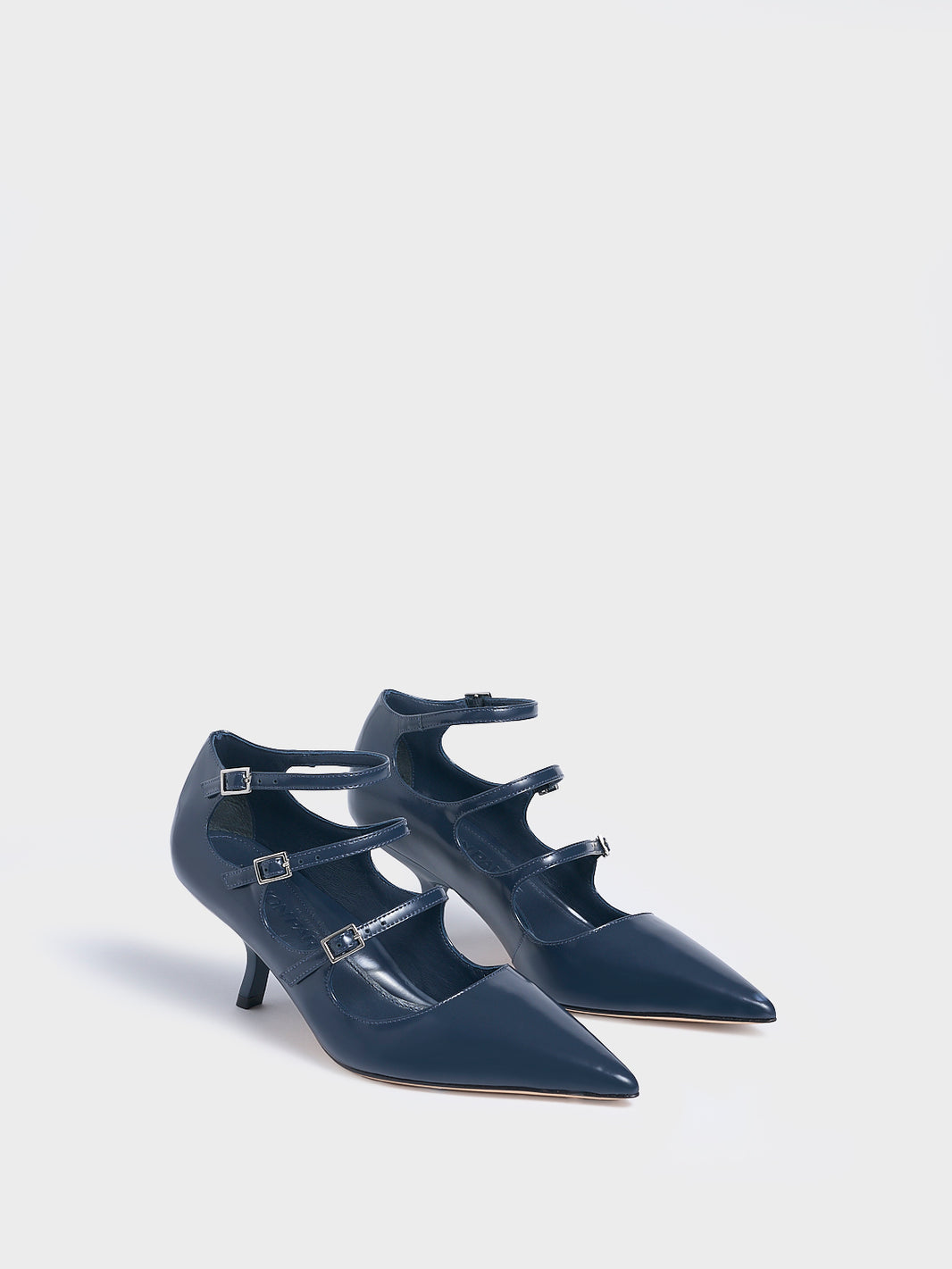 Angle view of a pair of navy blue brushed calf  leather mary jane heels with adjustable straps and a pointed toe. 