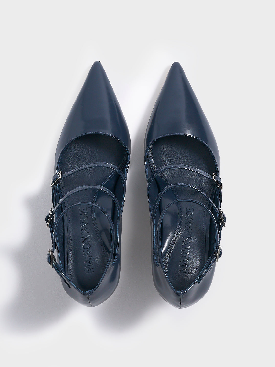 Top view of a pair of navy blue brushed calf  leather mary jane heels with adjustable straps and a pointed toe. 