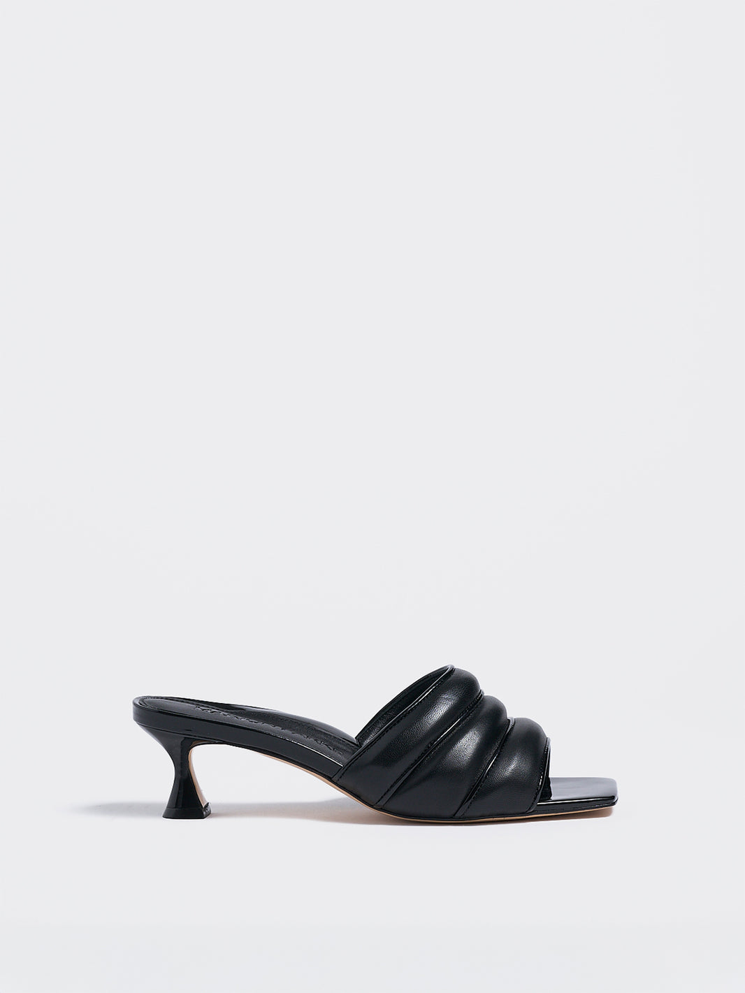 Profile view of a black leather slide kitten heel with a patent leather trimmed puffy strap detail.