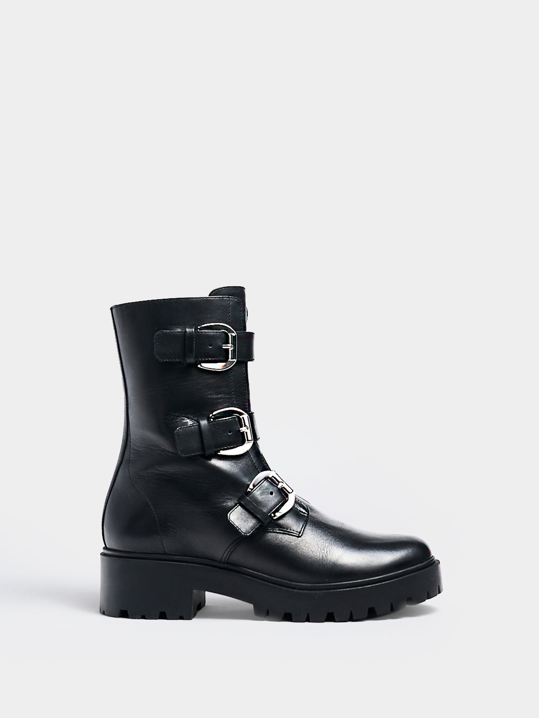 Profile view of a black nappa leather moto boot with a lug sole, zipper closure, silver buckles, and round toe. 