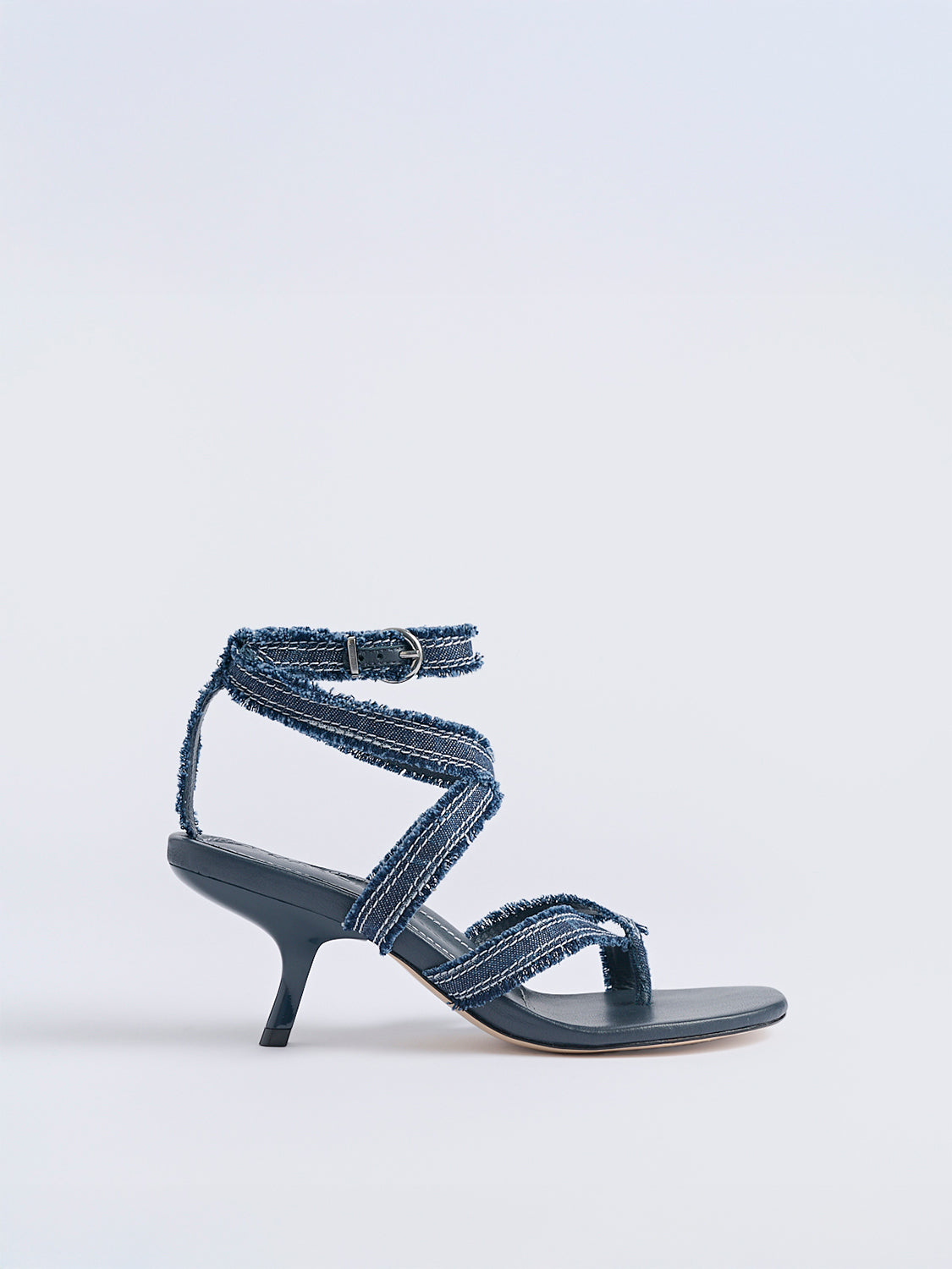 Profile view of a navy blue denim heel thong sandal with an angled heel and a rounded toe