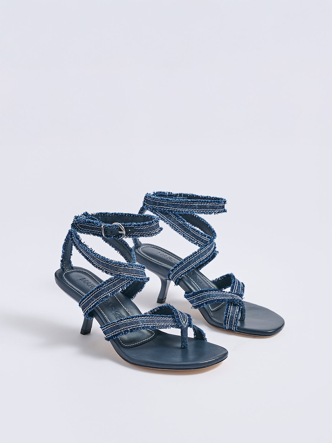 Angle view of a pair navy blue denim heel thong sandals with an angled heel and a rounded toe