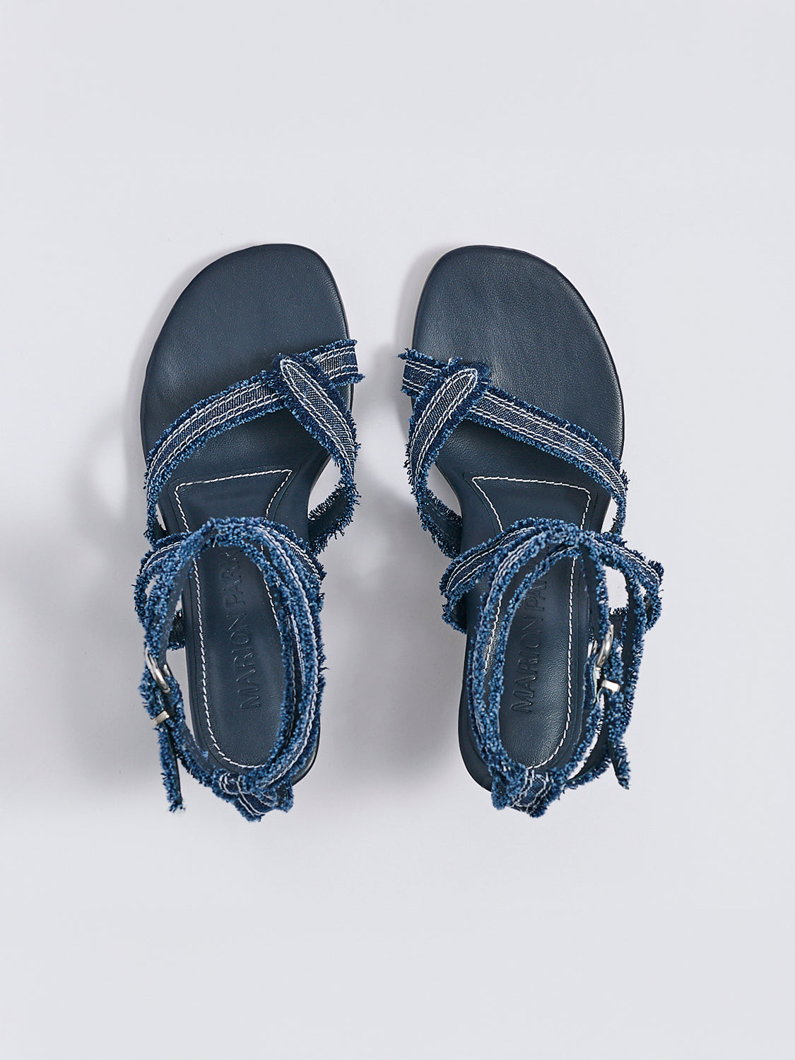 Top view of a pair navy blue denim heel thong sandals with an angled heel and a rounded toe