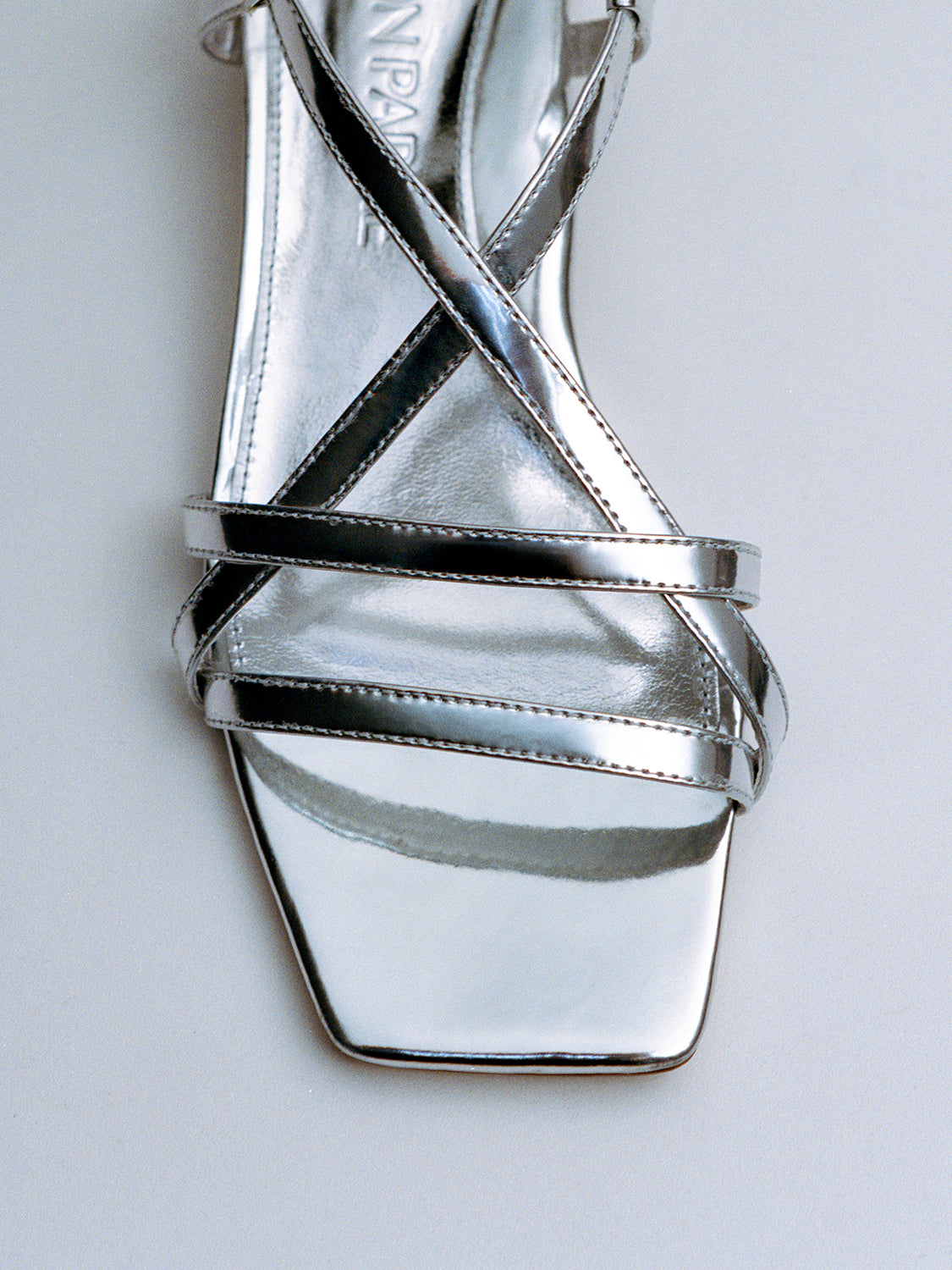 Top view of a silver metallic leather flat strappy sandal.