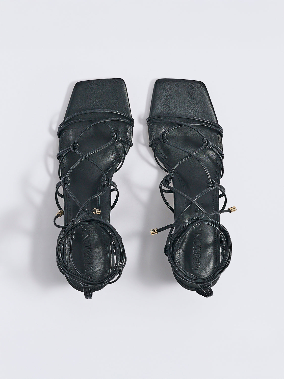 Top view of a pair of black leather lace up block heel sandals with a square toe