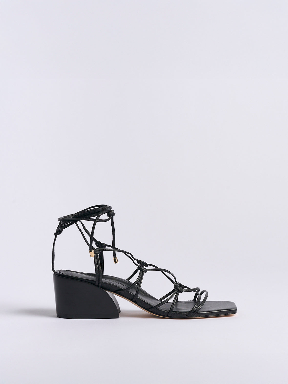 Profile view of a black leather lace up block heel sandal with a square toe