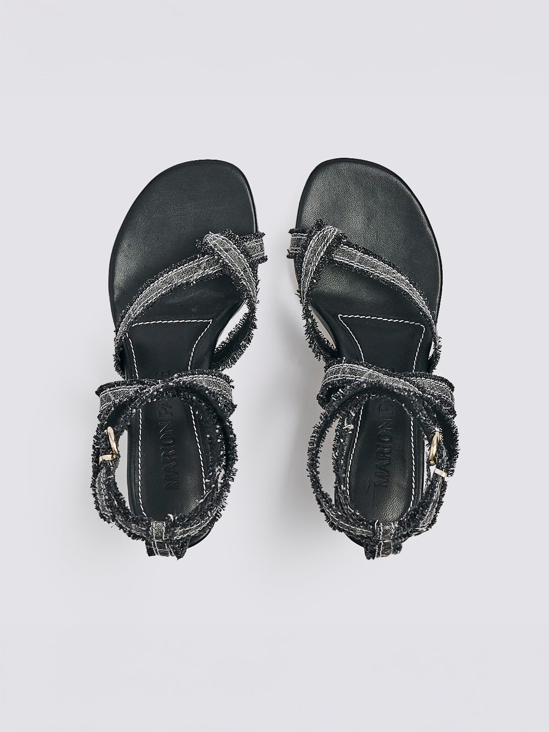 Top view of a pair of black denim thong  sandals with an angled heel and a rounded toe