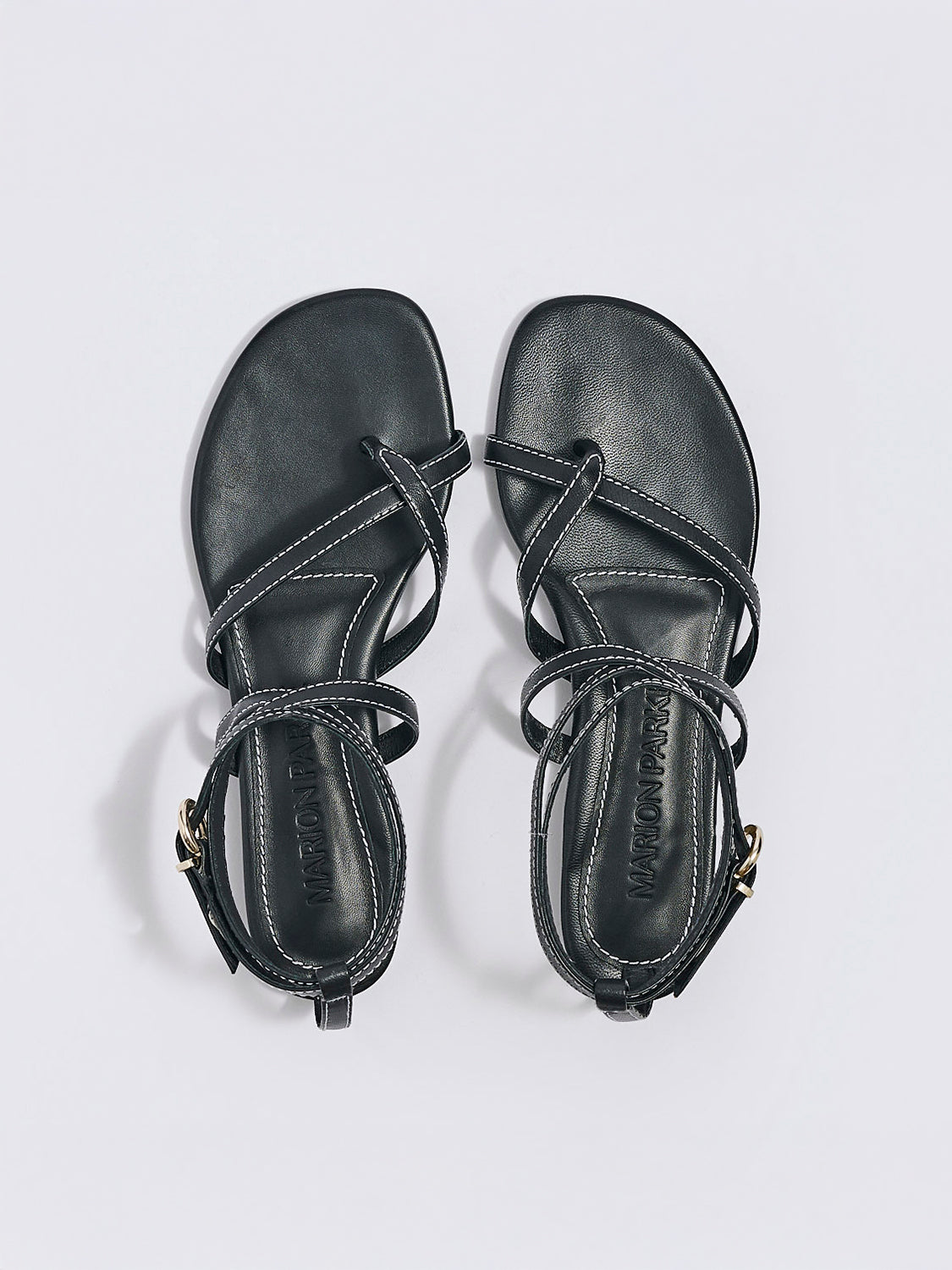 Top view of a pair of black leather thong flat sandals with a rounded toe