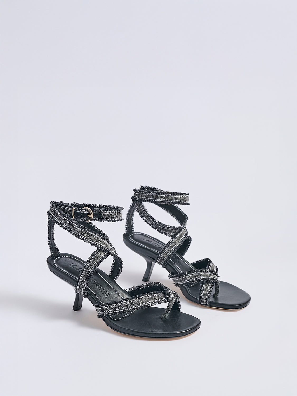 Angle view of a pair of black denim thong  sandals with an angled heel and a rounded toe