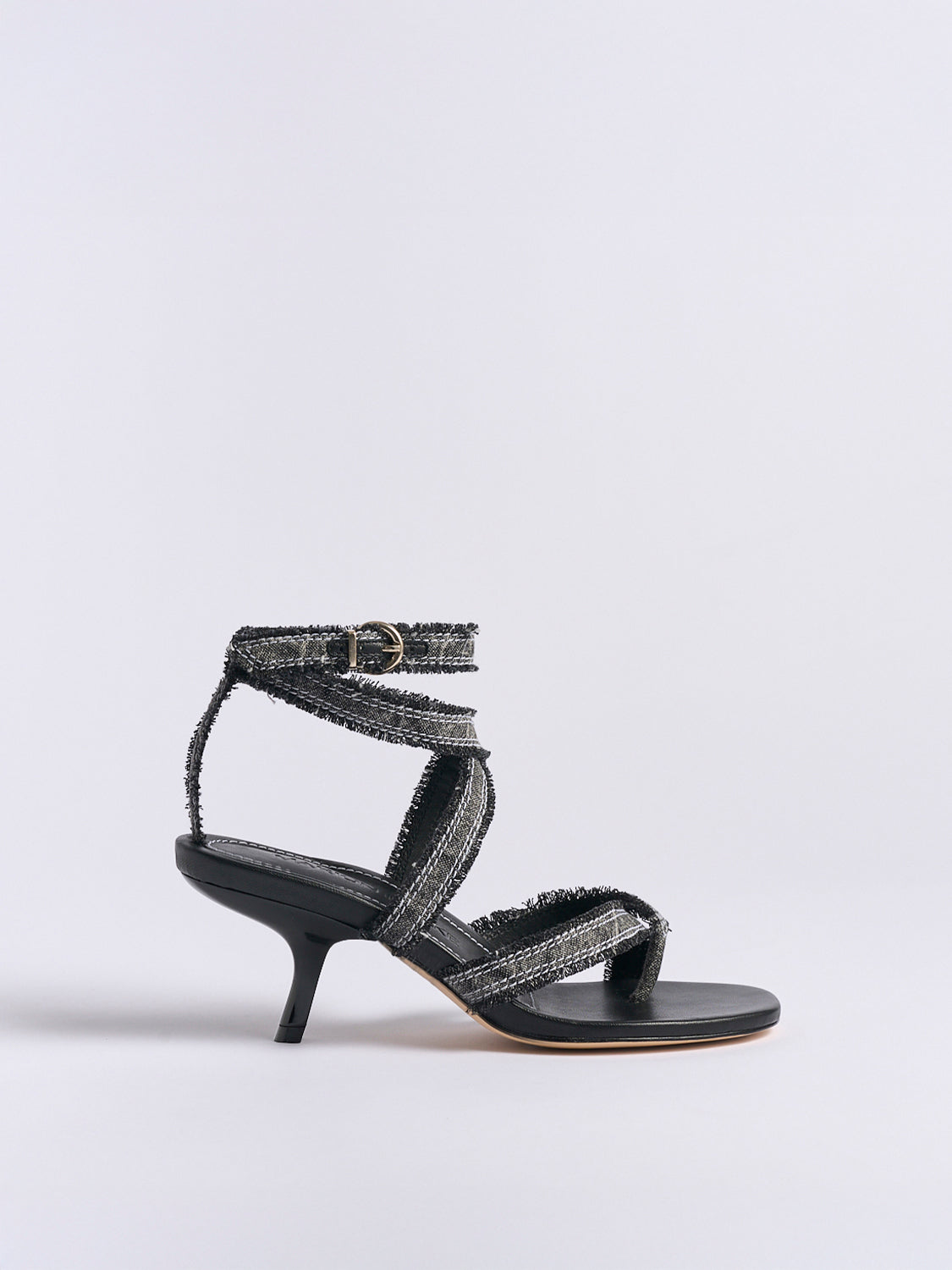 Profile view of a black denim thong  sandal with an angled heel and a rounded toe