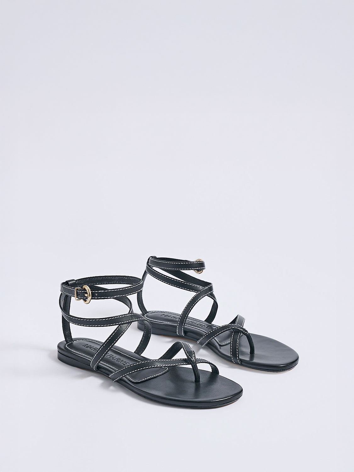 Angle view of a pair of black leather thong flat sandals with a rounded toe