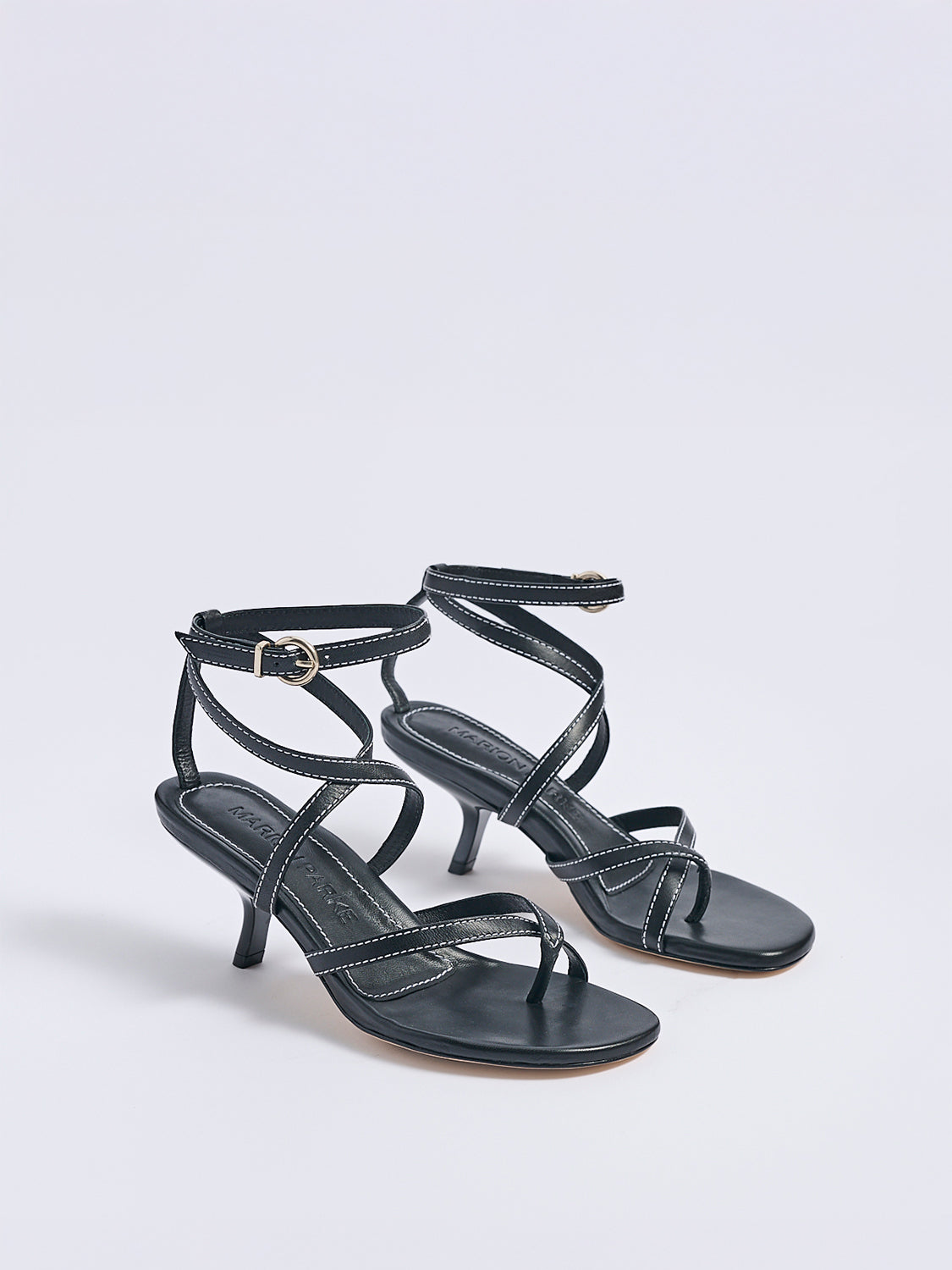 Angle view of a pair of black leather thong  sandals with an angled heel and a rounded toe
