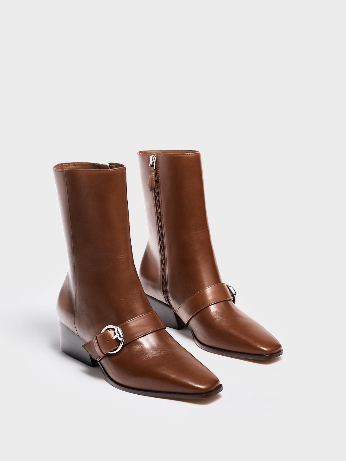 Profile view of a mocha brown nappa leather ankle bootie with a zipper closure, silver buckle, and block heel. 