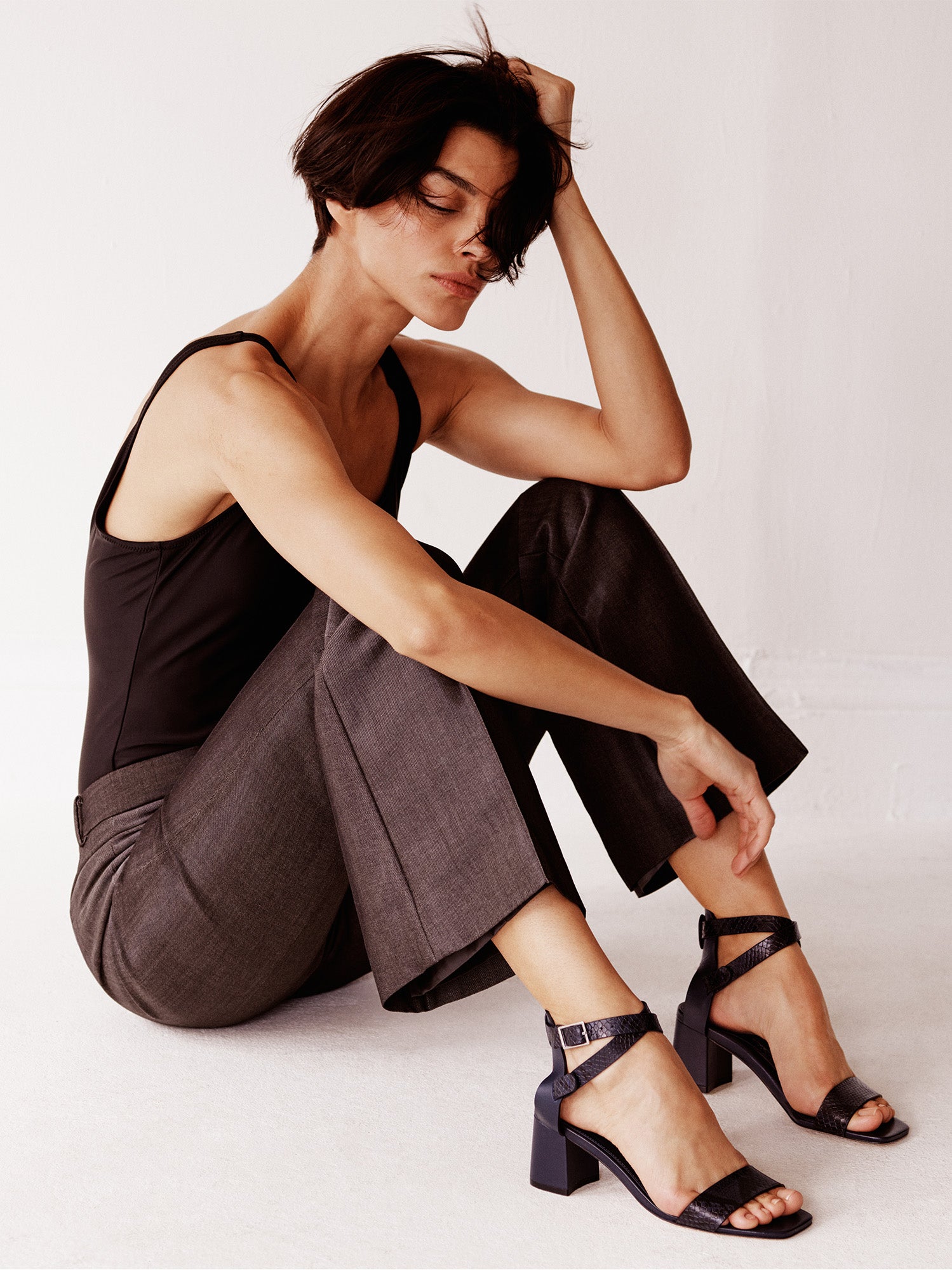 Navy python leather block heel sandals with an adjustable ankle strap design, shown on a model.