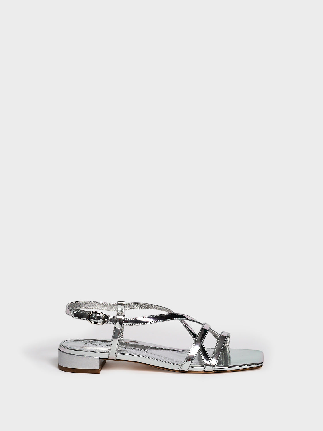 Profile view of a silver metallic leather flat strappy sandal.