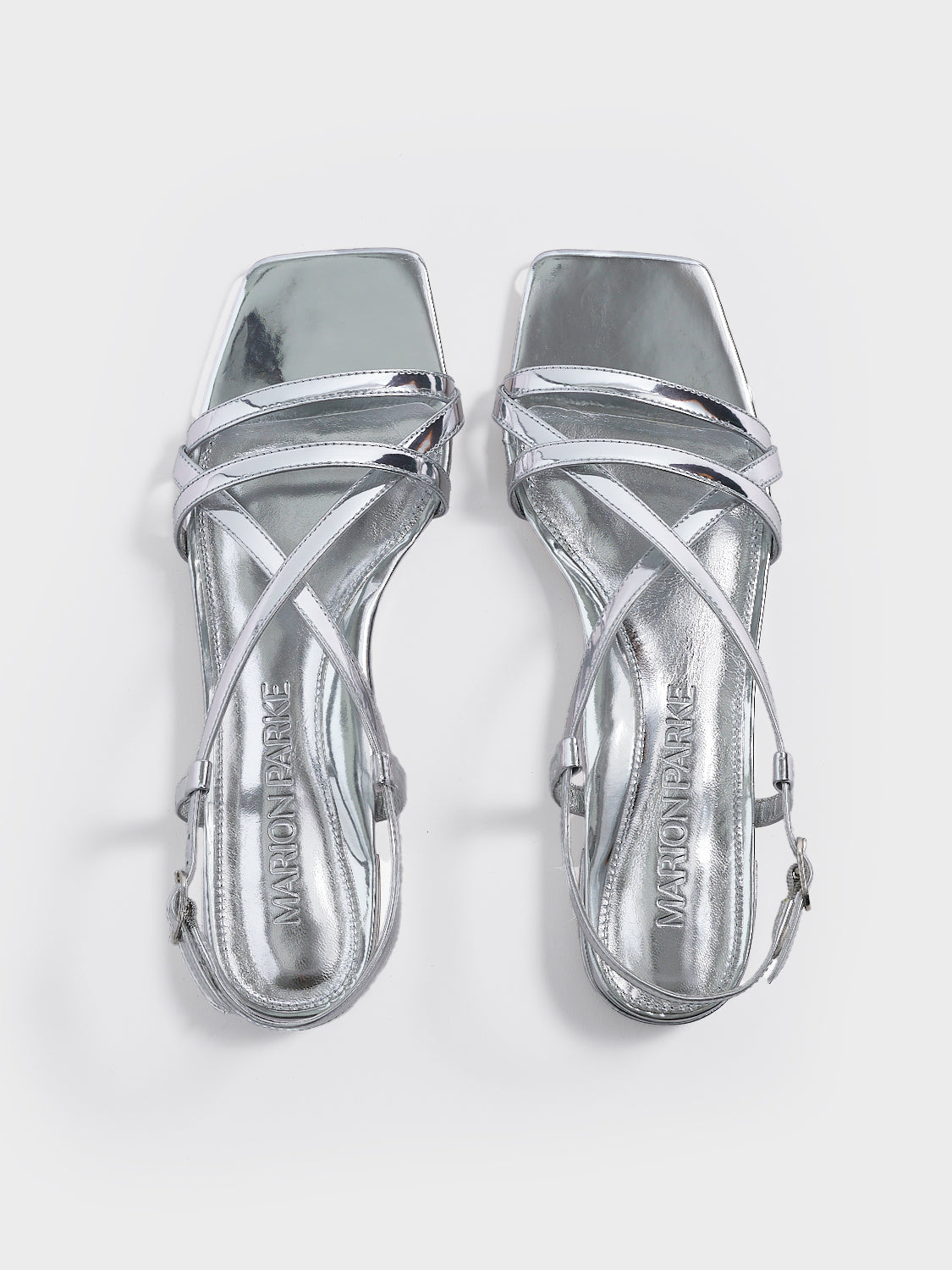 Top view of a pair of silver metallic leather flat strappy sandals.