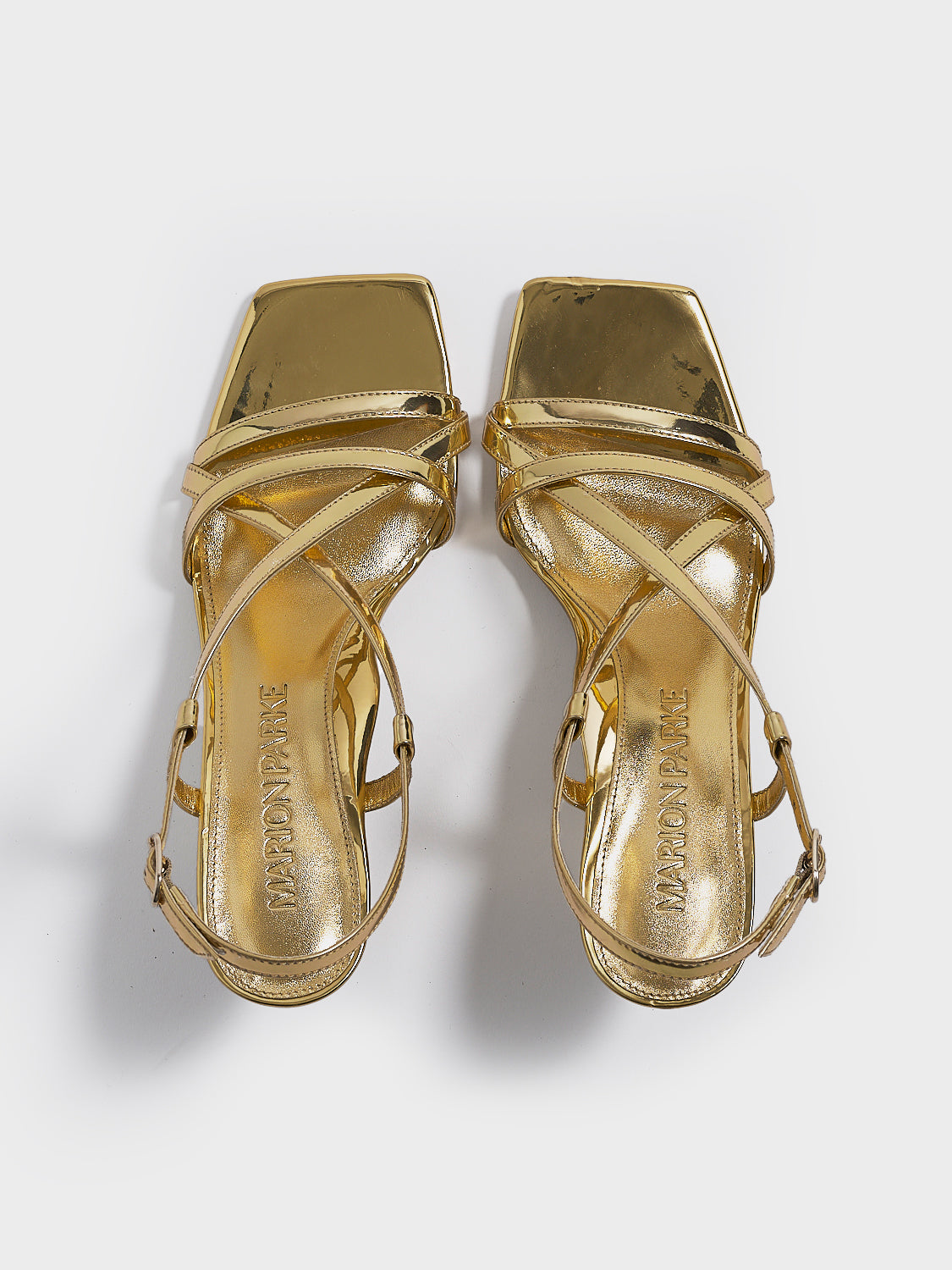 Top view of a pair of gold metallic leather strappy sandals with a sculptural wedge.