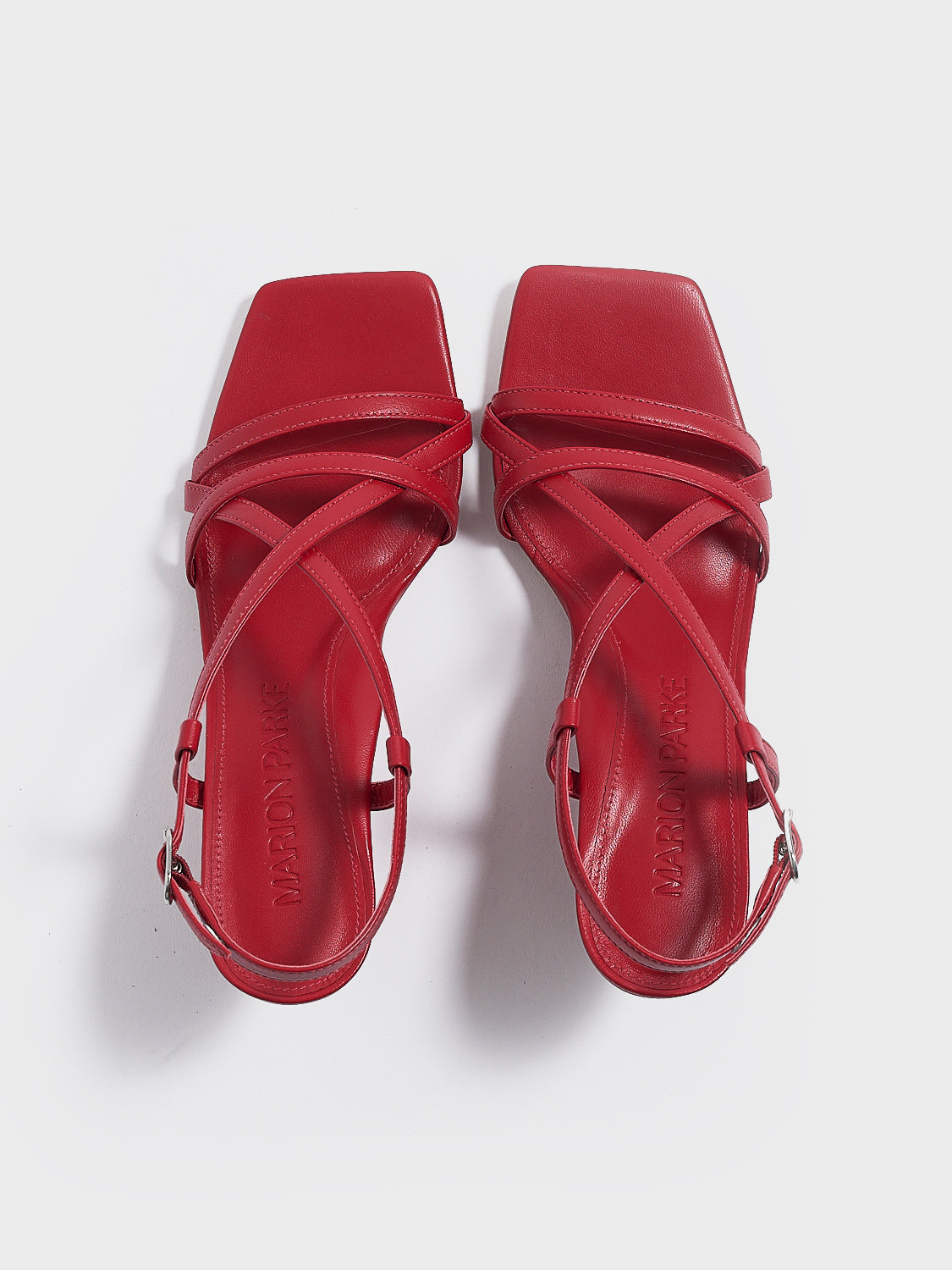 Top view of a pair of lipstick red leather strappy sandals with a sculptural wedge.