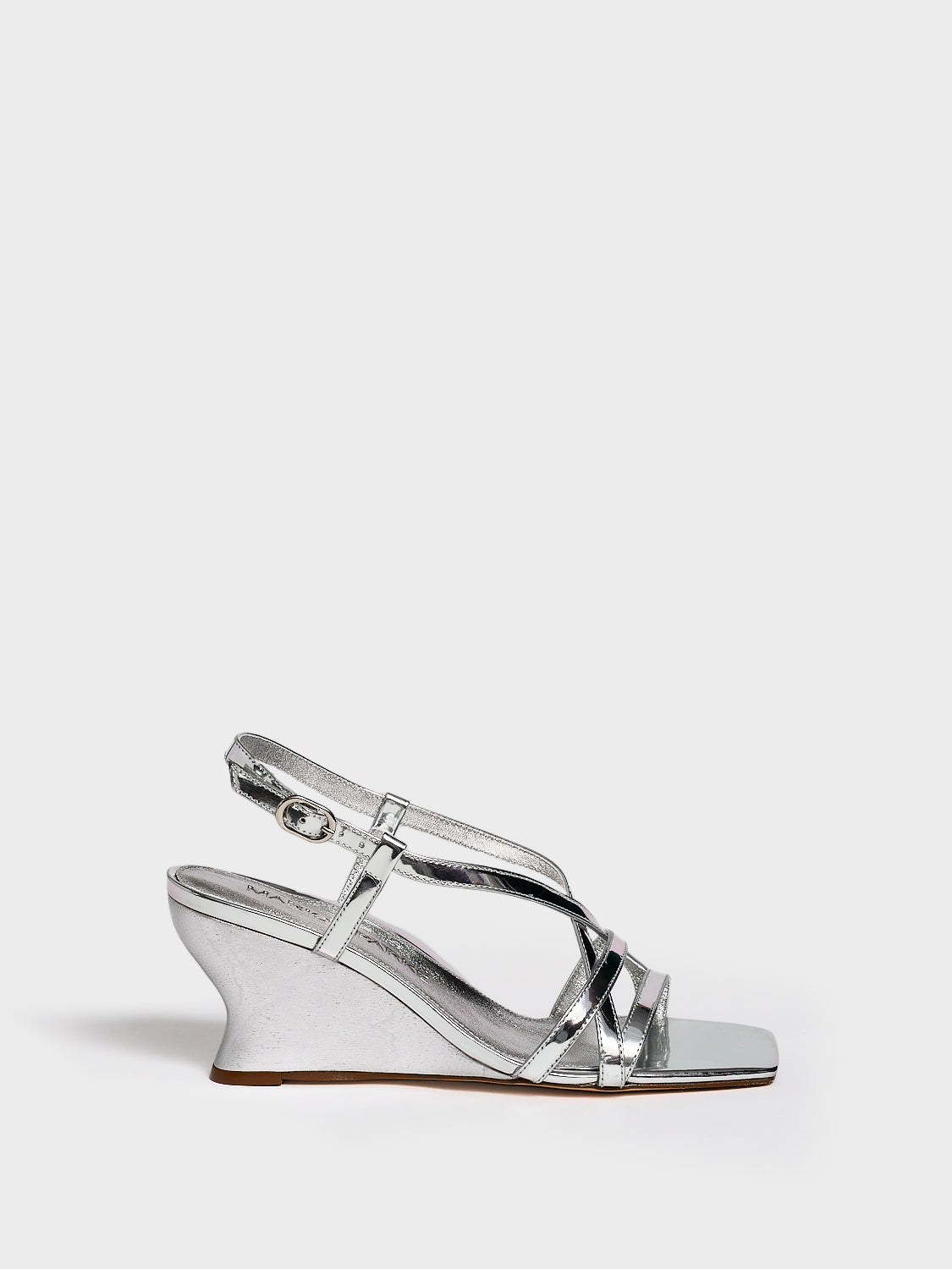 Profile view of a silver metallic leather strappy sandal with a sculptural wedge.